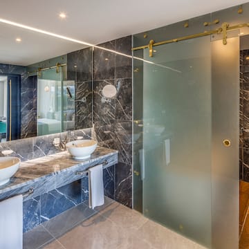 a bathroom with marble countertops and a glass shower