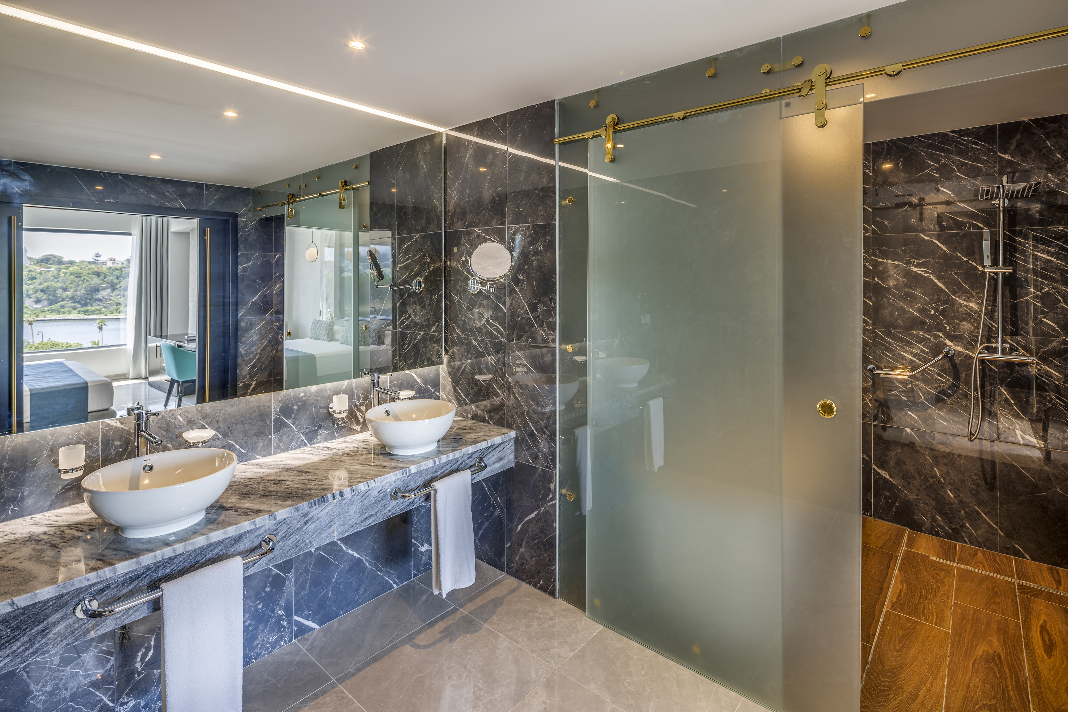 a bathroom with marble countertops and a glass shower