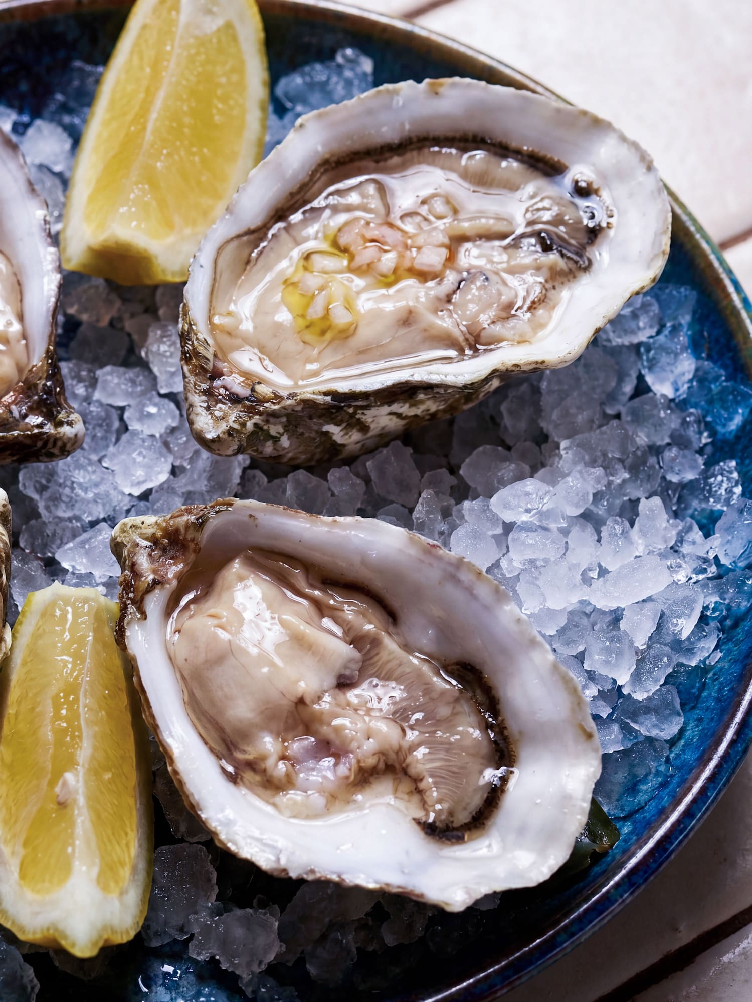 Raw oysters on half shell, served on crushed ice with fresh lemon wedges.