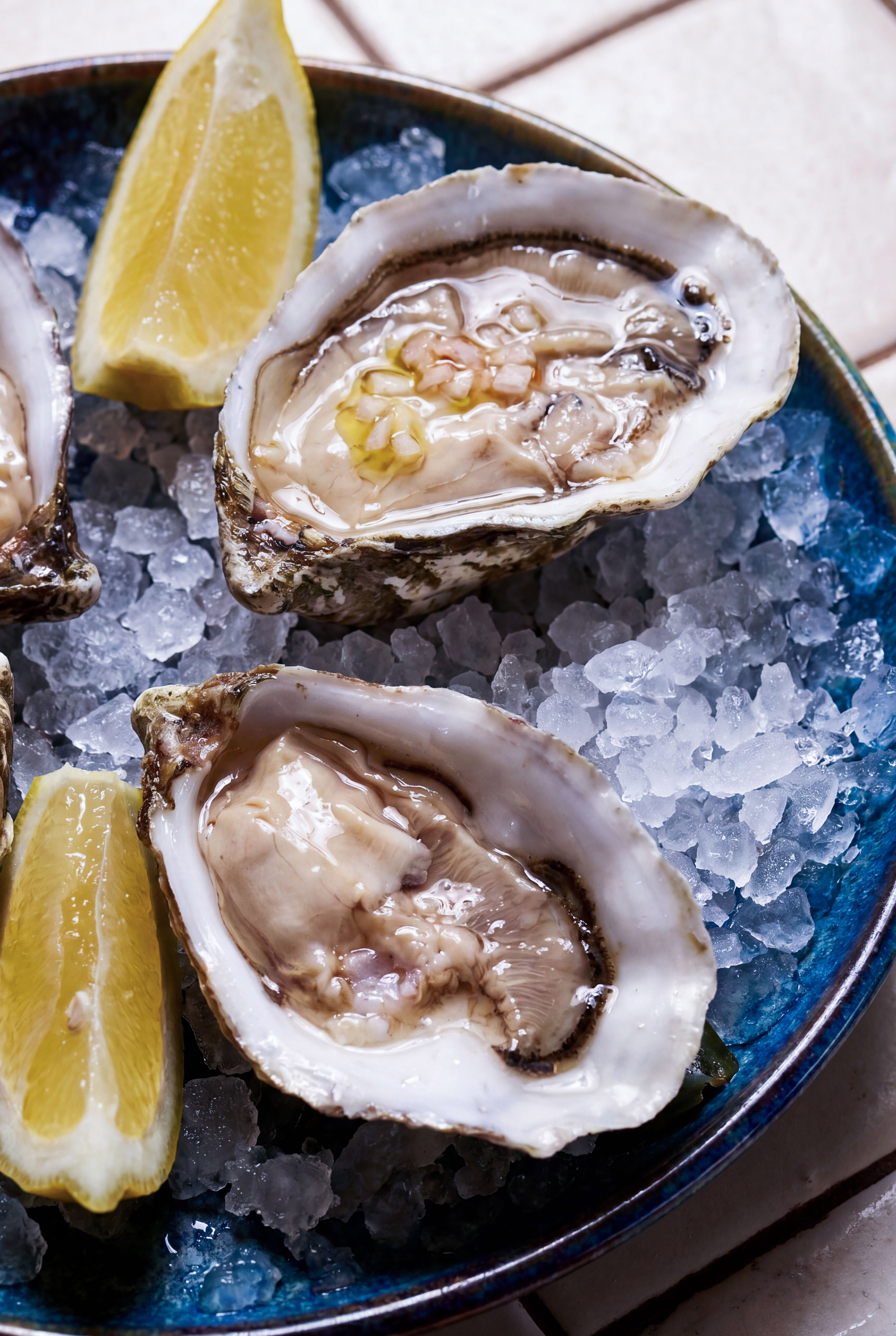 Raw oysters on half shell, served on crushed ice with fresh lemon wedges.