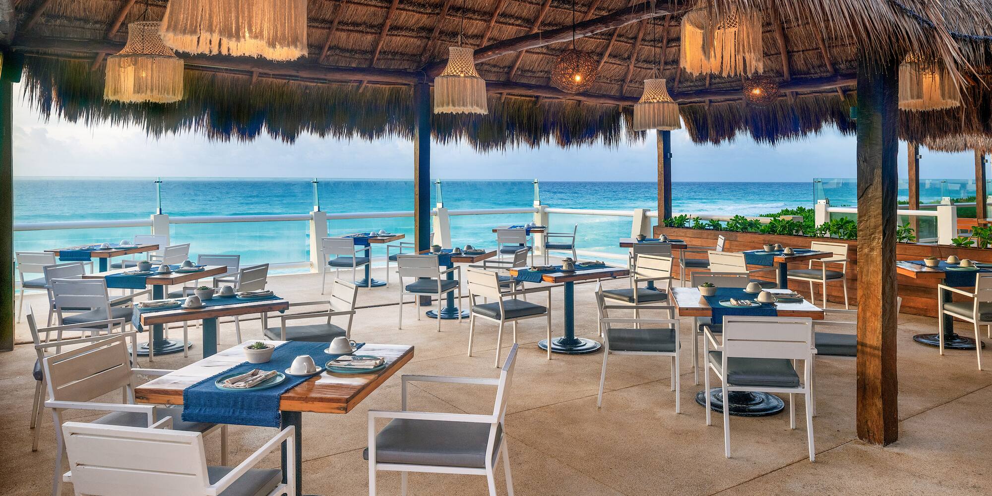 a restaurant with a thatched roof and tables and chairs