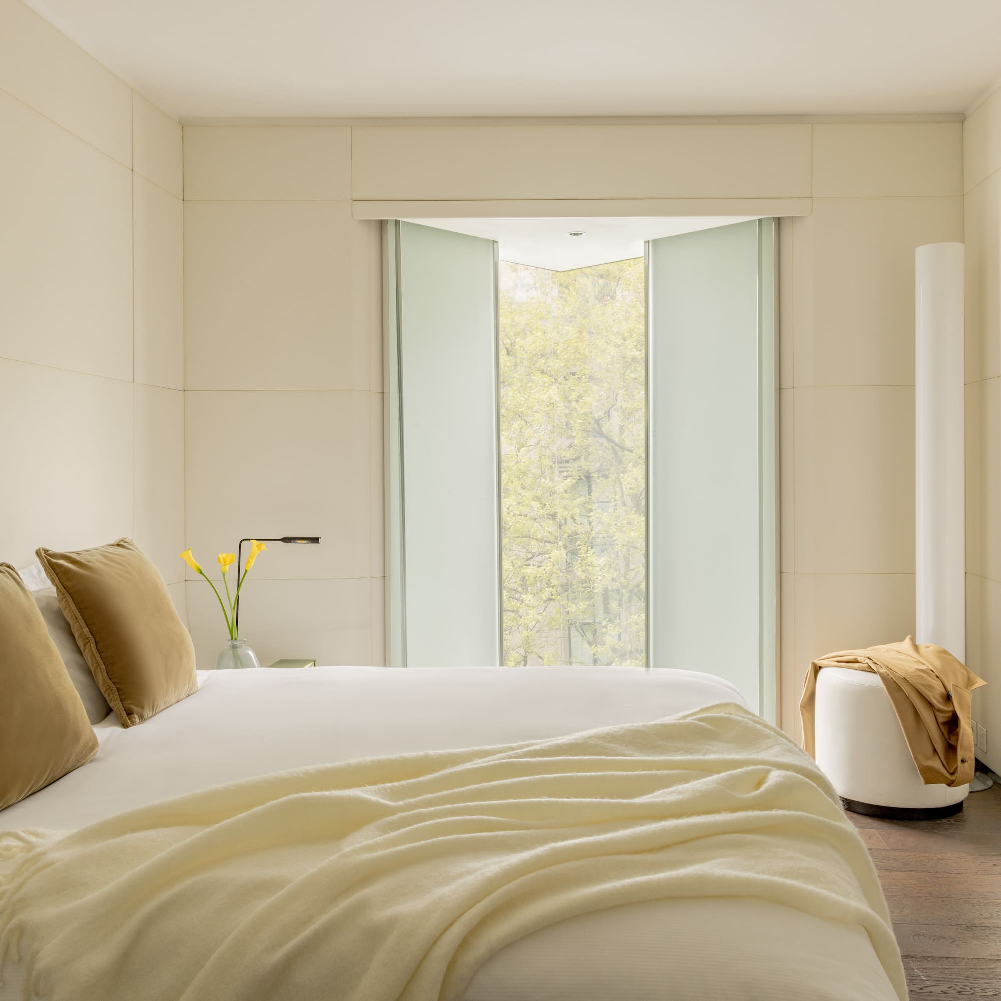 a bed with pillows and a vase of flowers in front of a window