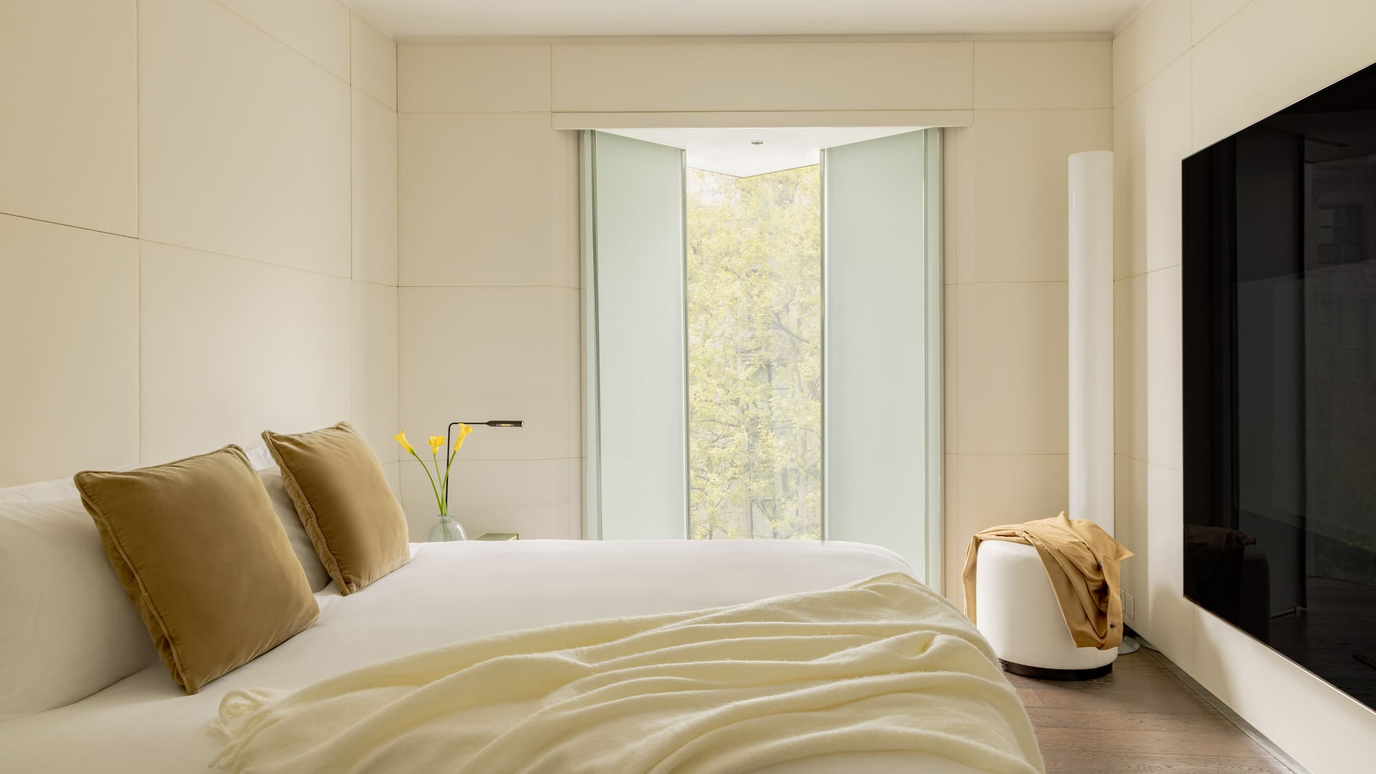 a bed with pillows and a vase of flowers in front of a window