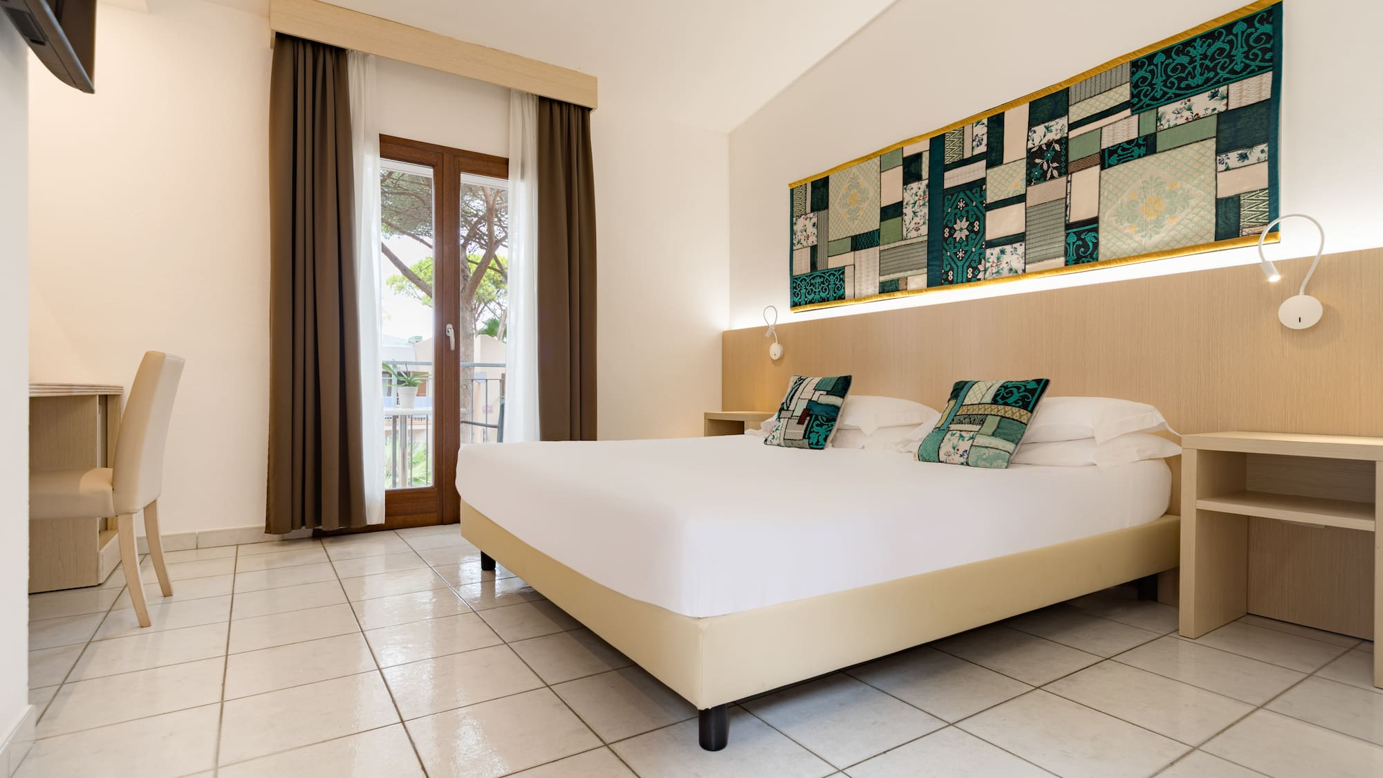 Spacious hotel bedroom with a queen bed, balcony, and patterned wall decor.