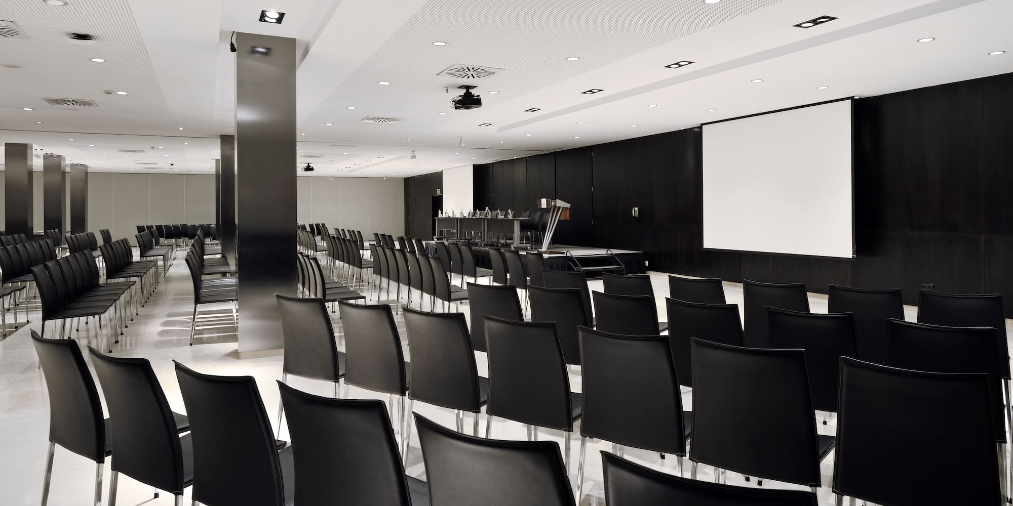 a room with black chairs and a projector screen
