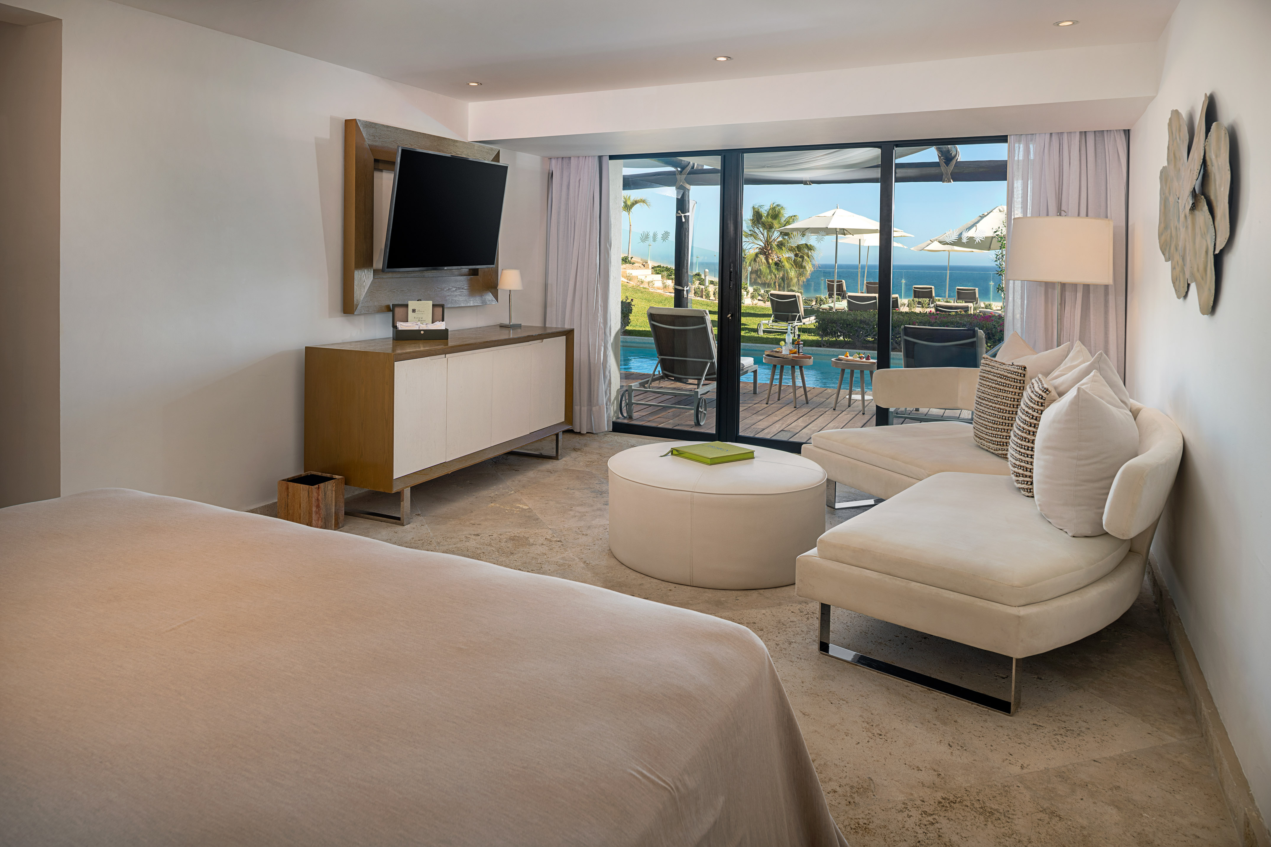 Modern hotel bedroom suite with ocean view, private pool, and patio.