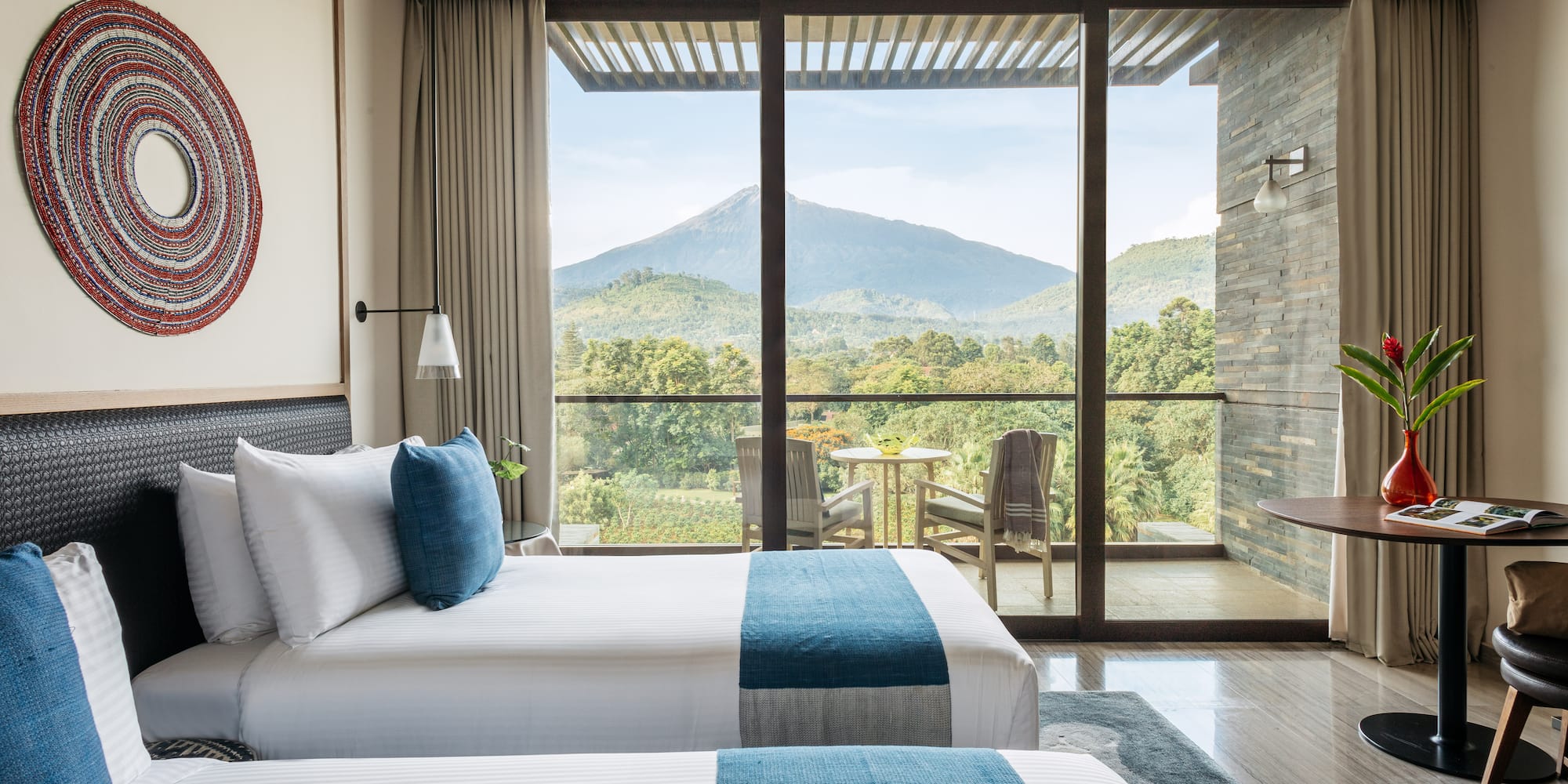 two beds in a room with a view of mountains and trees