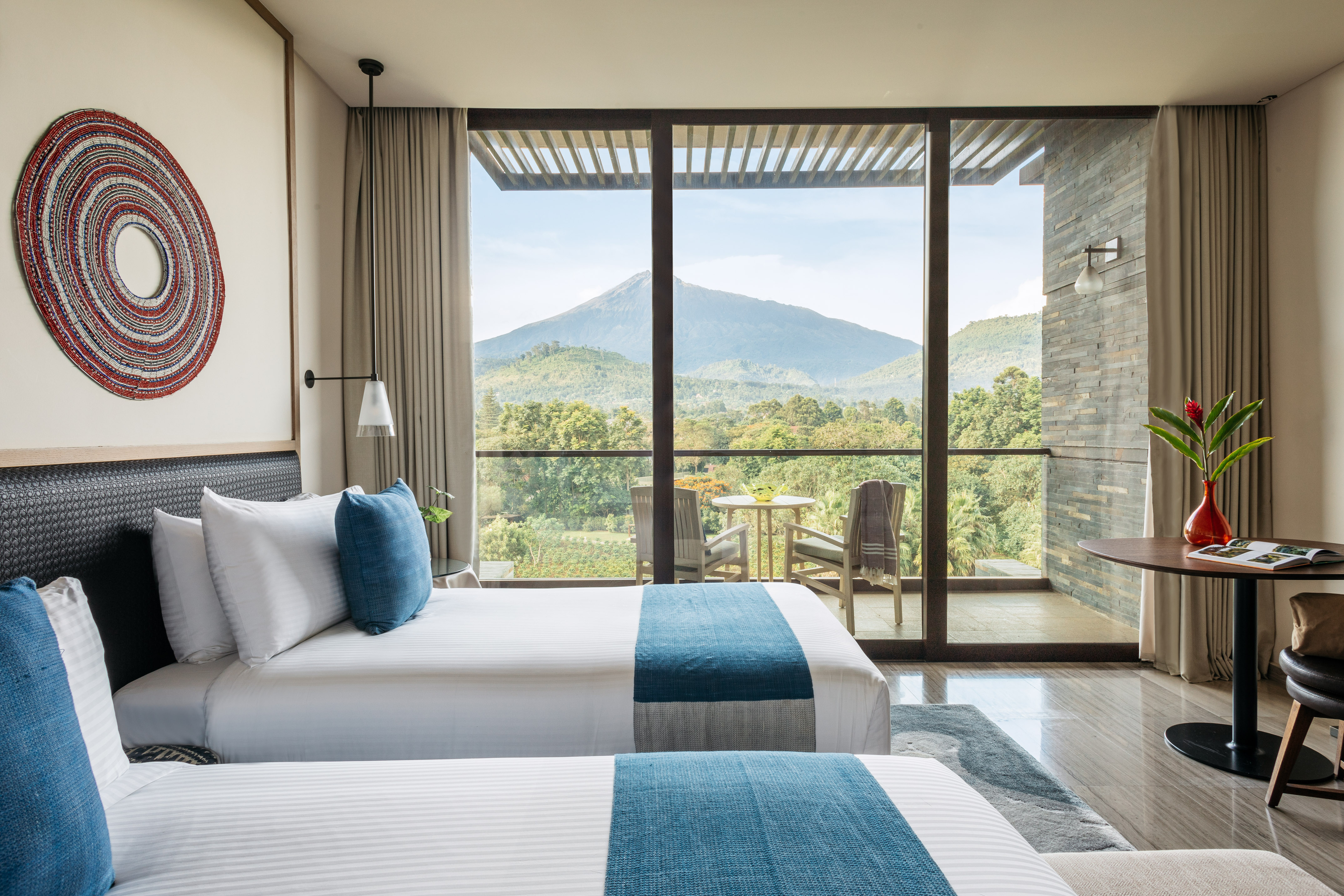 two beds in a room with a view of mountains and trees