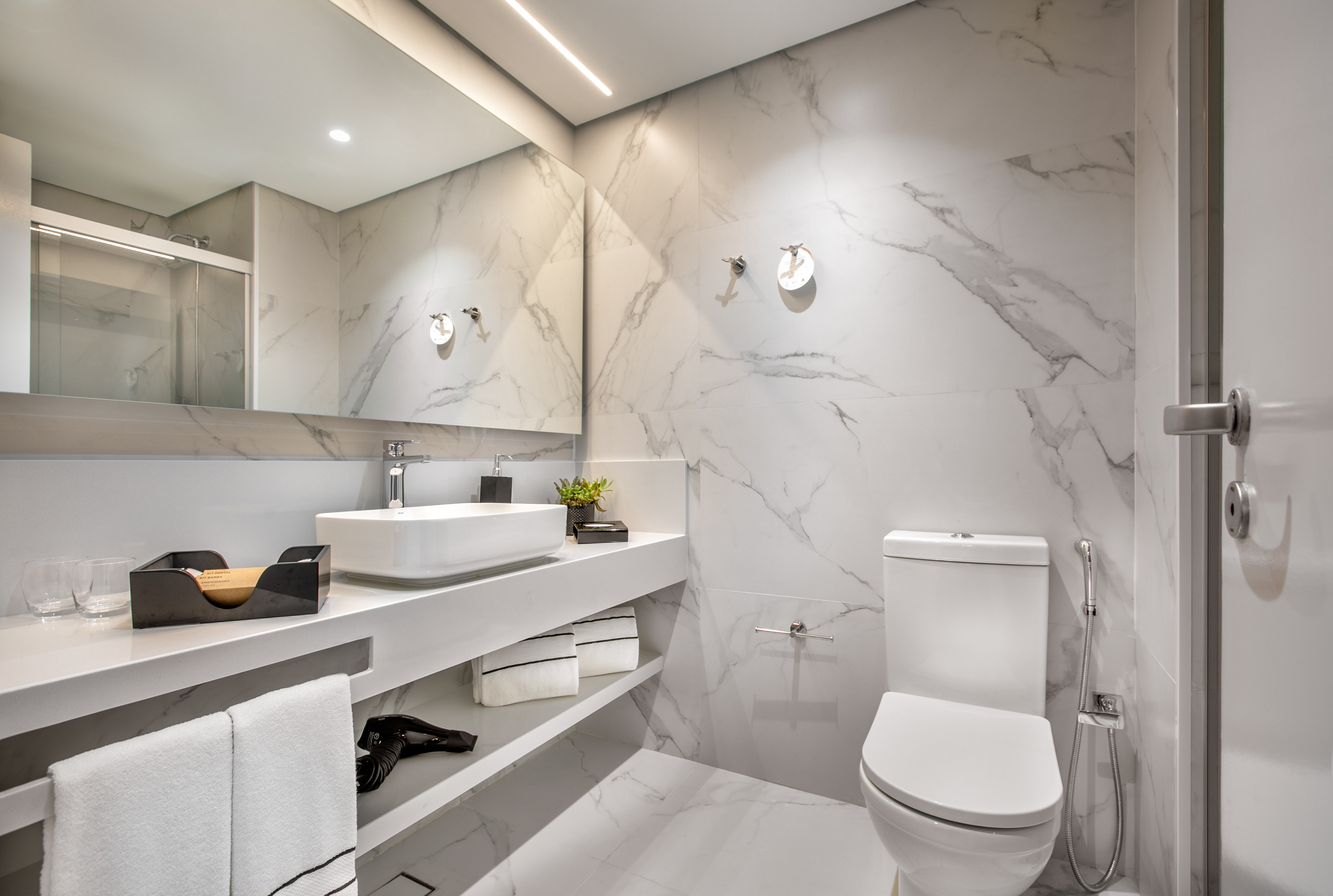 a bathroom with marble walls and a sink and toilet