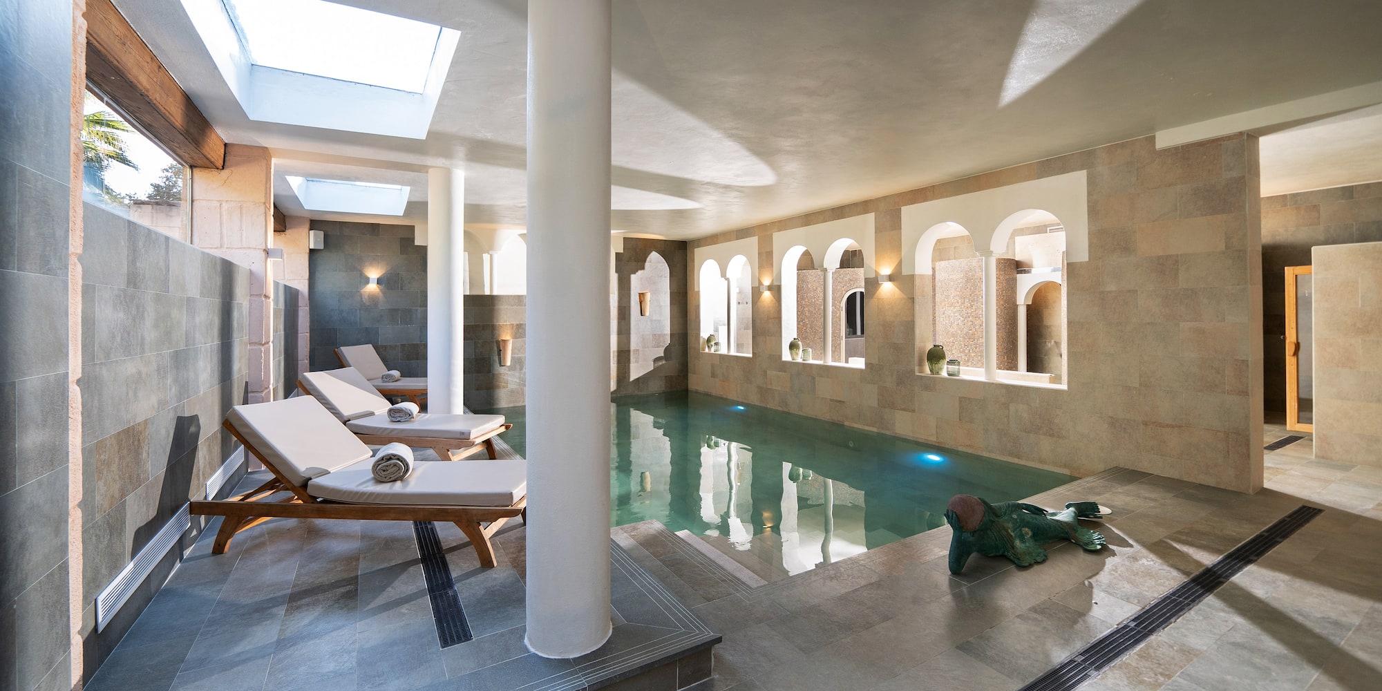 a pool with chairs and a statue in it