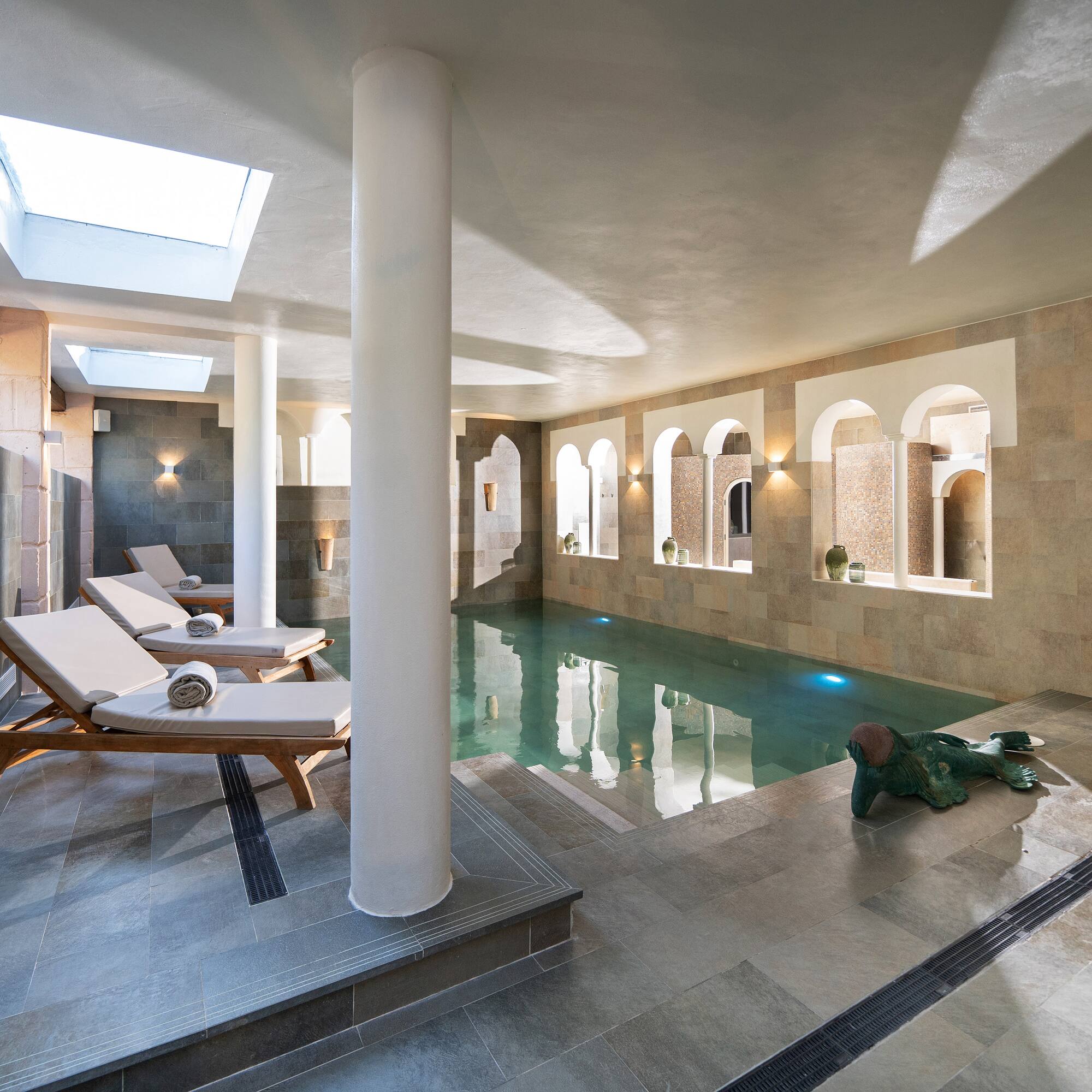 a pool with chairs and a statue in it