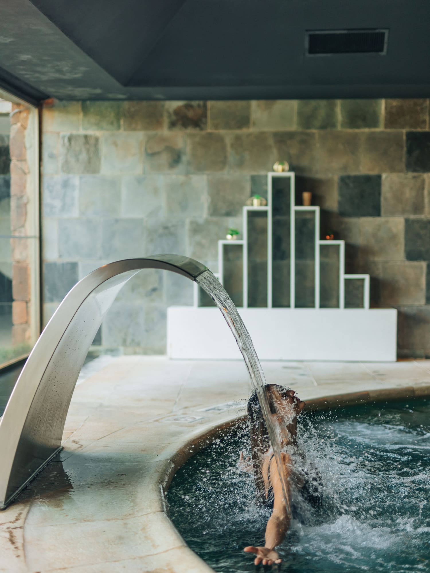 a person in a pool with water coming out of the water