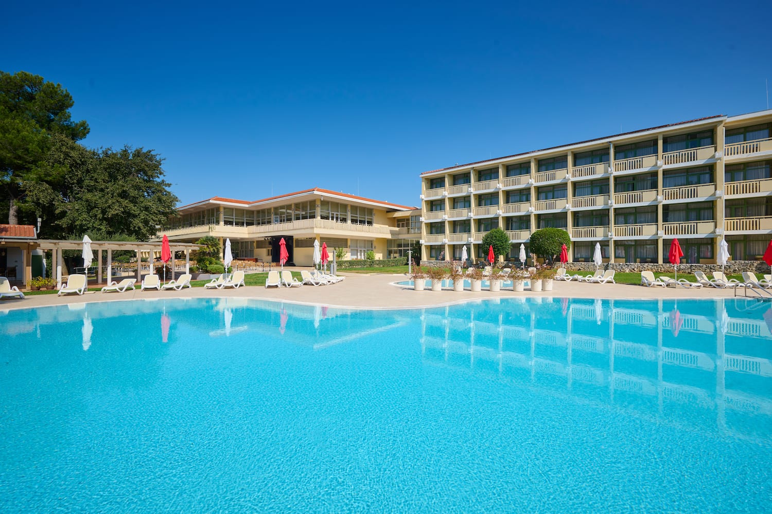 a pool with umbrellas and chairs in front of a building