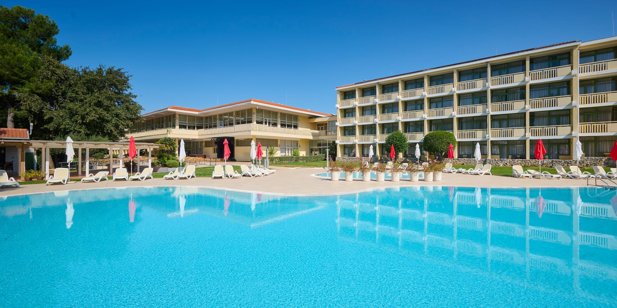 a pool with umbrellas and chairs in front of a building
