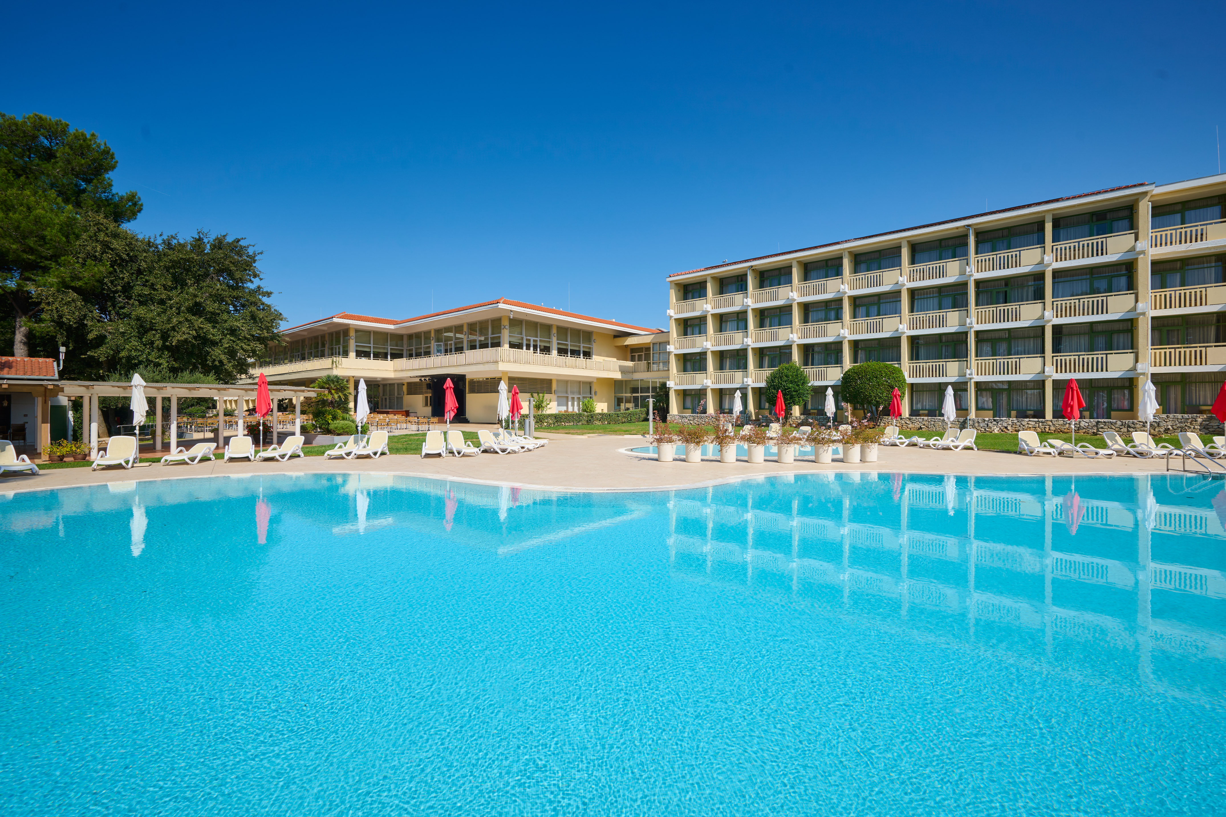a pool with umbrellas and chairs in front of a building