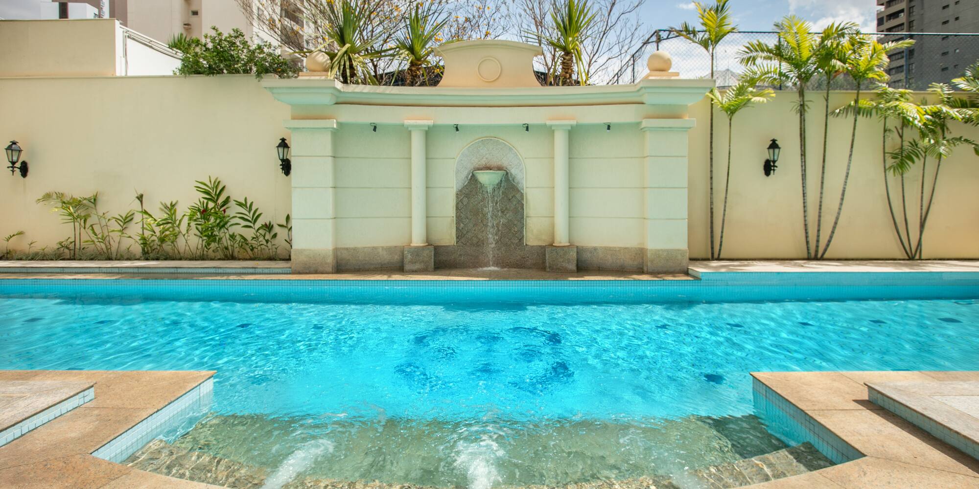 a pool with a fountain and a fence