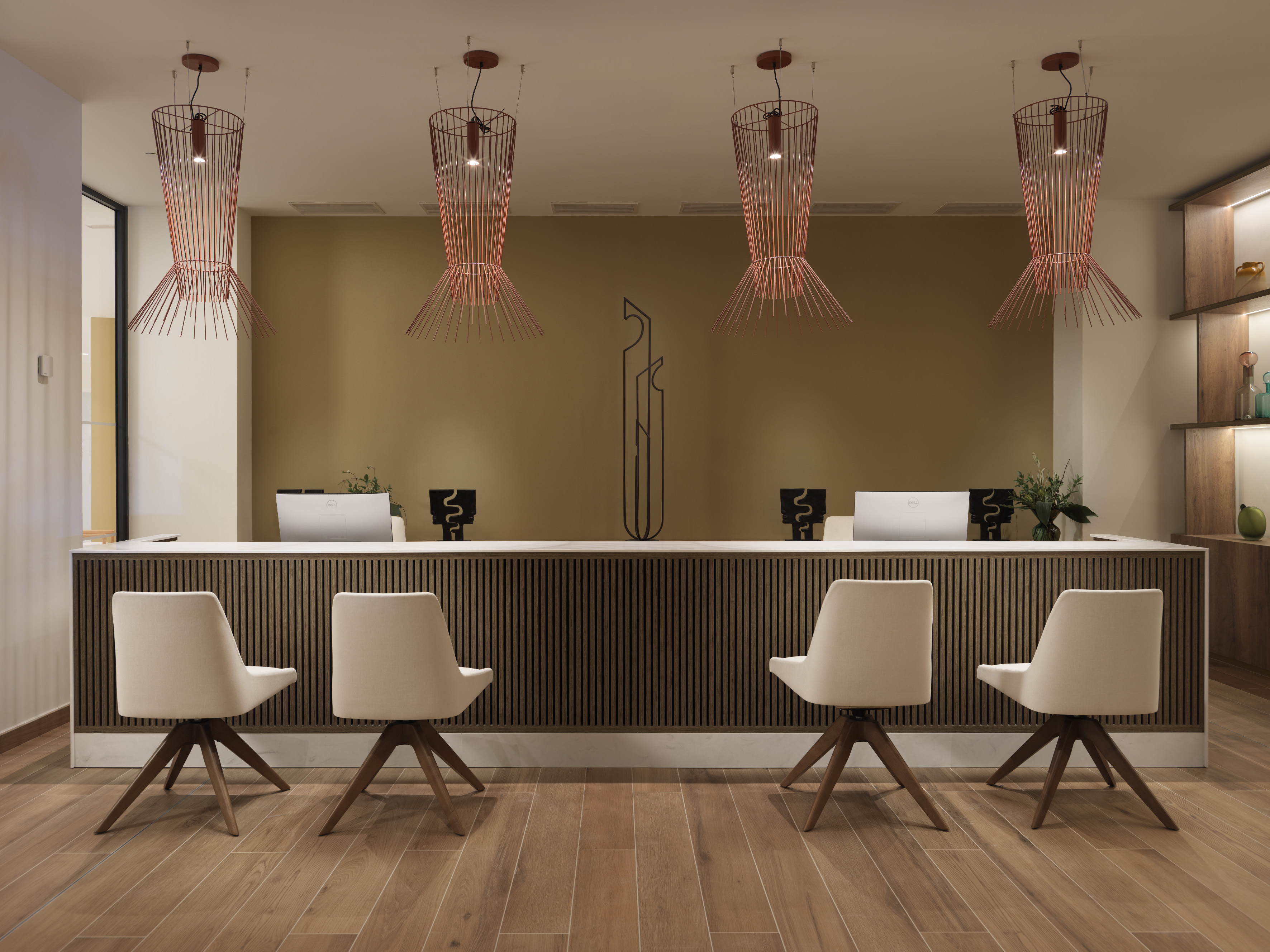 Modern hotel reception desk with four chairs and stylish wire pendant lights.