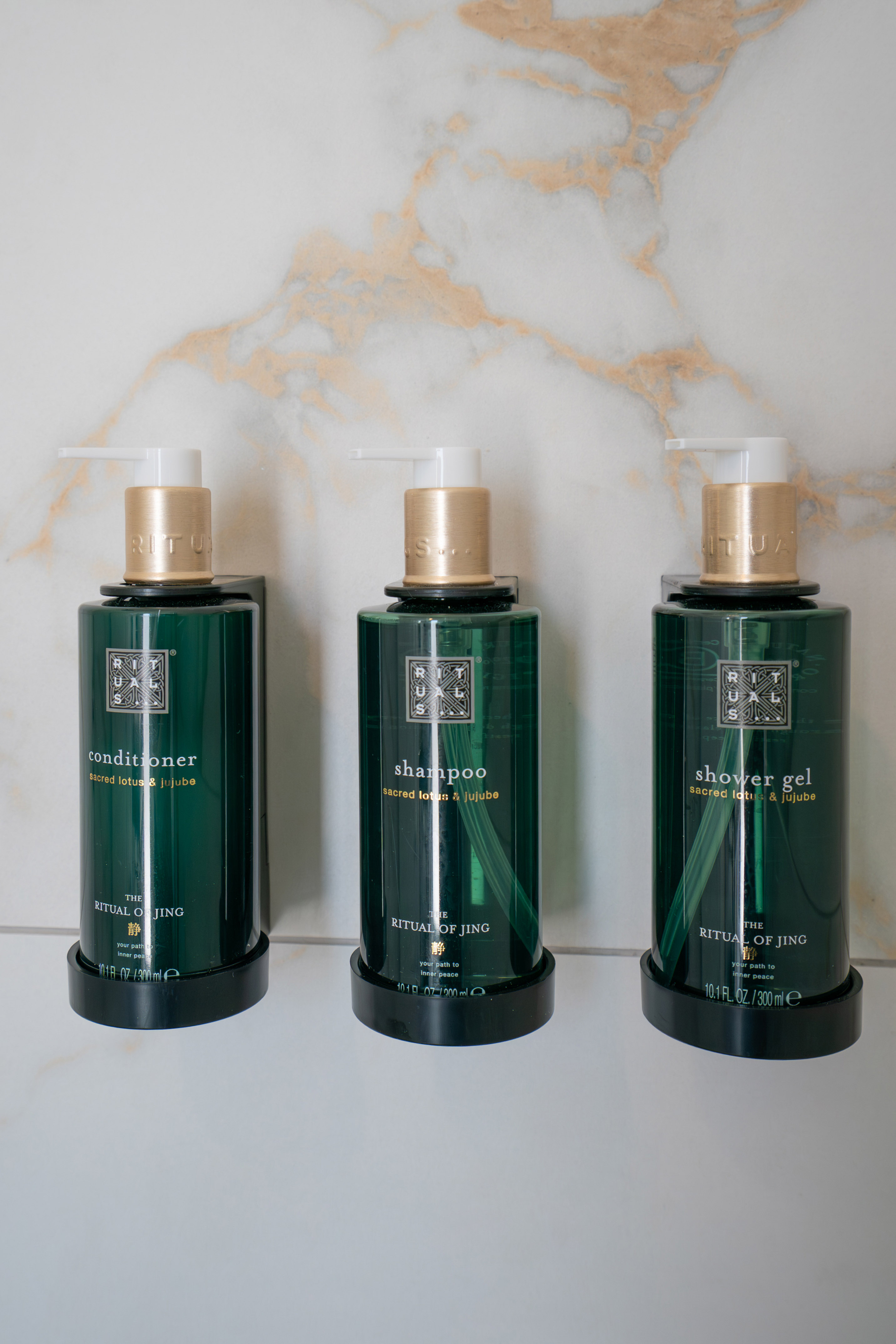 Rituals The Ritual of Jing lotus & jujube shampoo, conditioner, shower gel on marble.