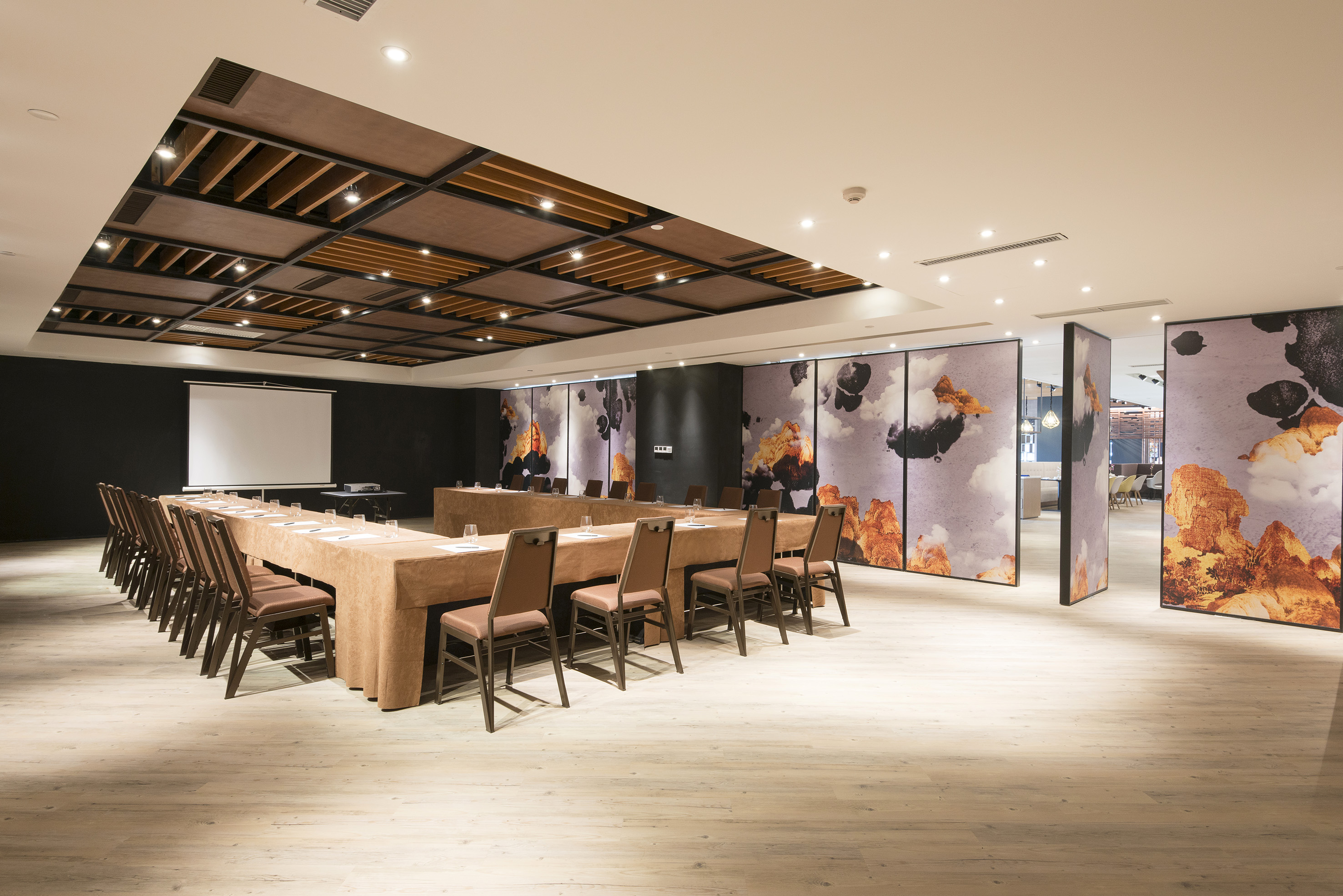 Modern conference room with U-shaped table, projector screen, and stylish wall art.