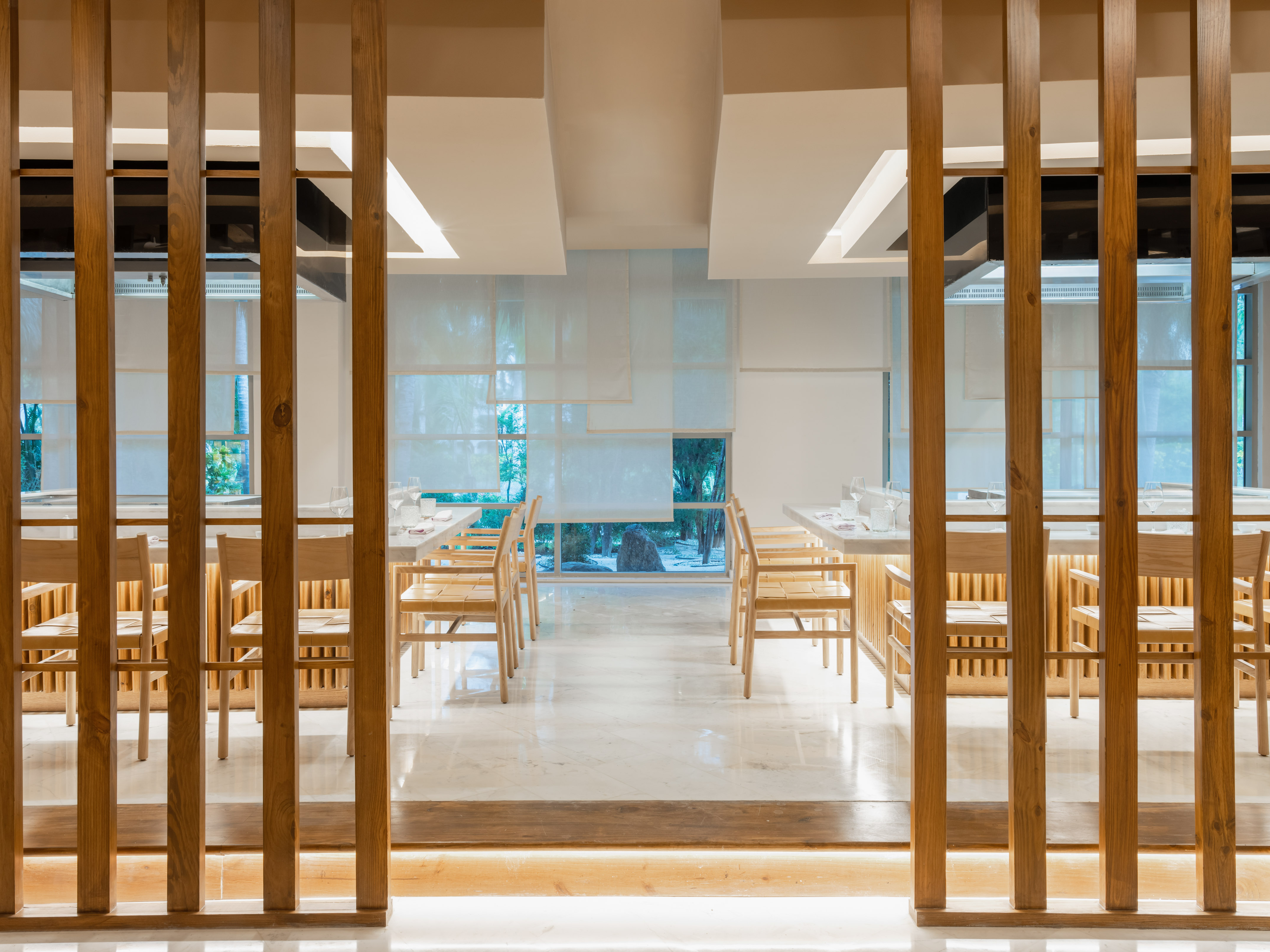 Bright, modern restaurant interior with wooden dividers and minimalist furniture.