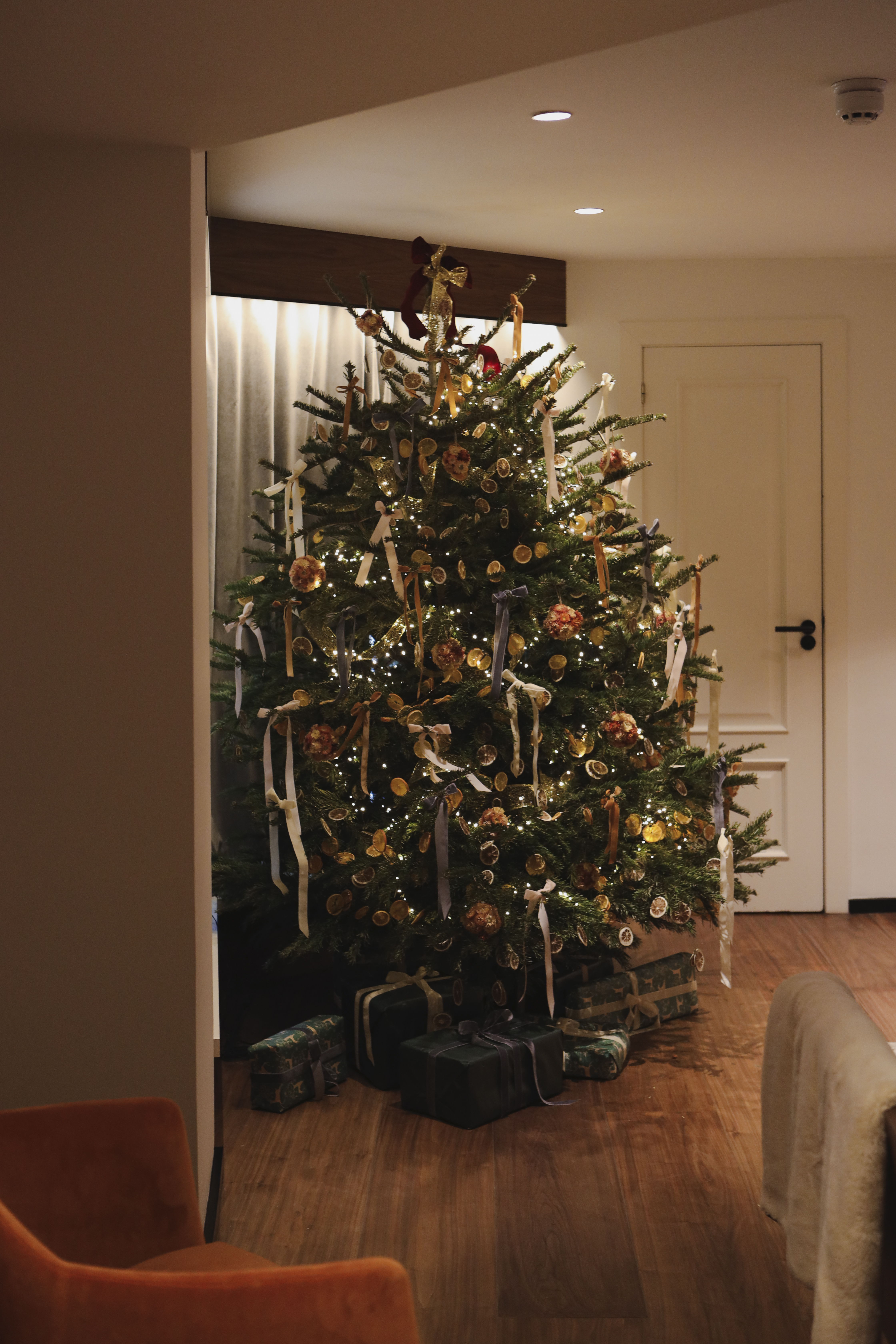 Festive Christmas tree decorated with lights, dried oranges, ribbons, and gifts.