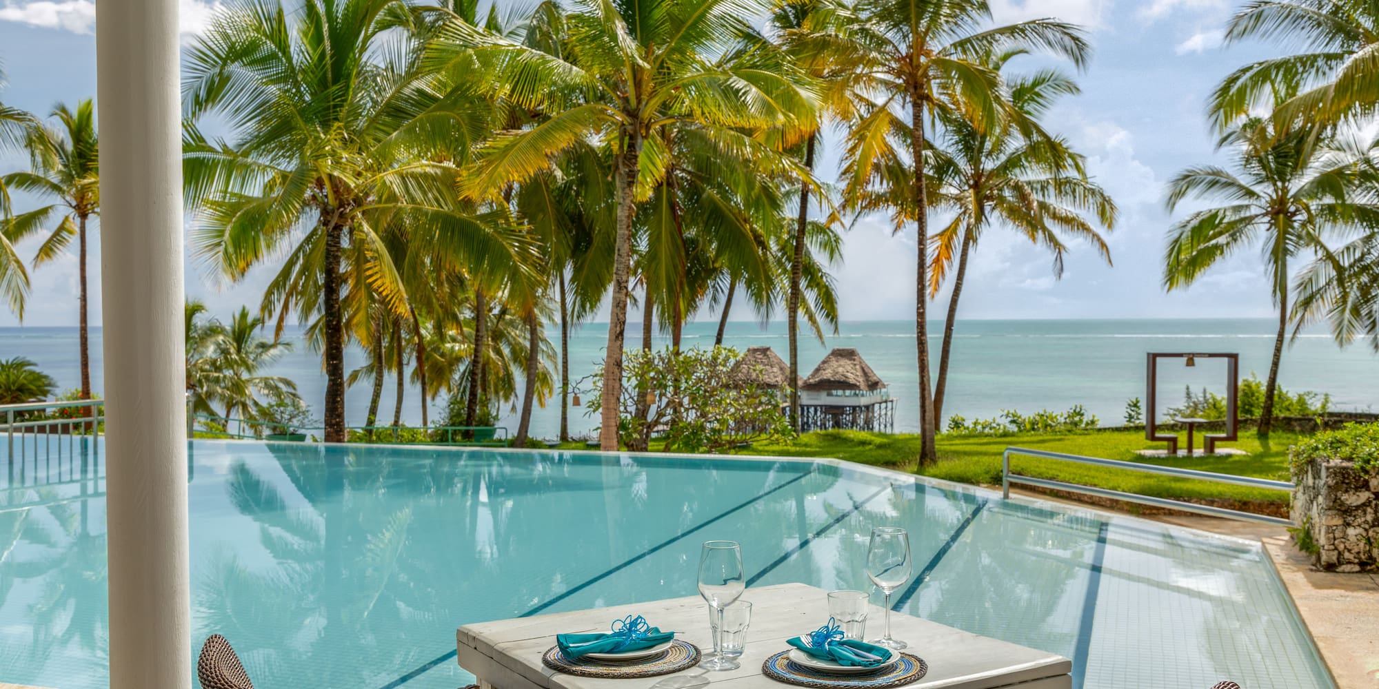 a table and chairs by a pool with palm trees