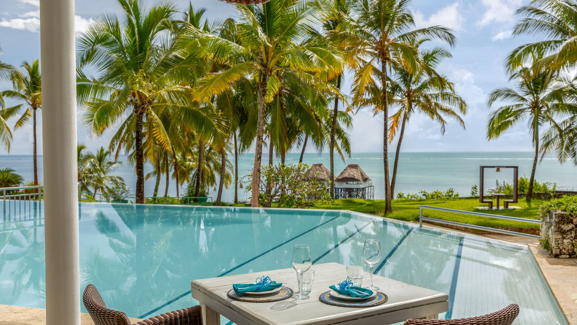 a table and chairs by a pool with palm trees