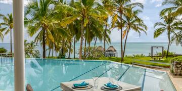 a table and chairs by a pool with palm trees