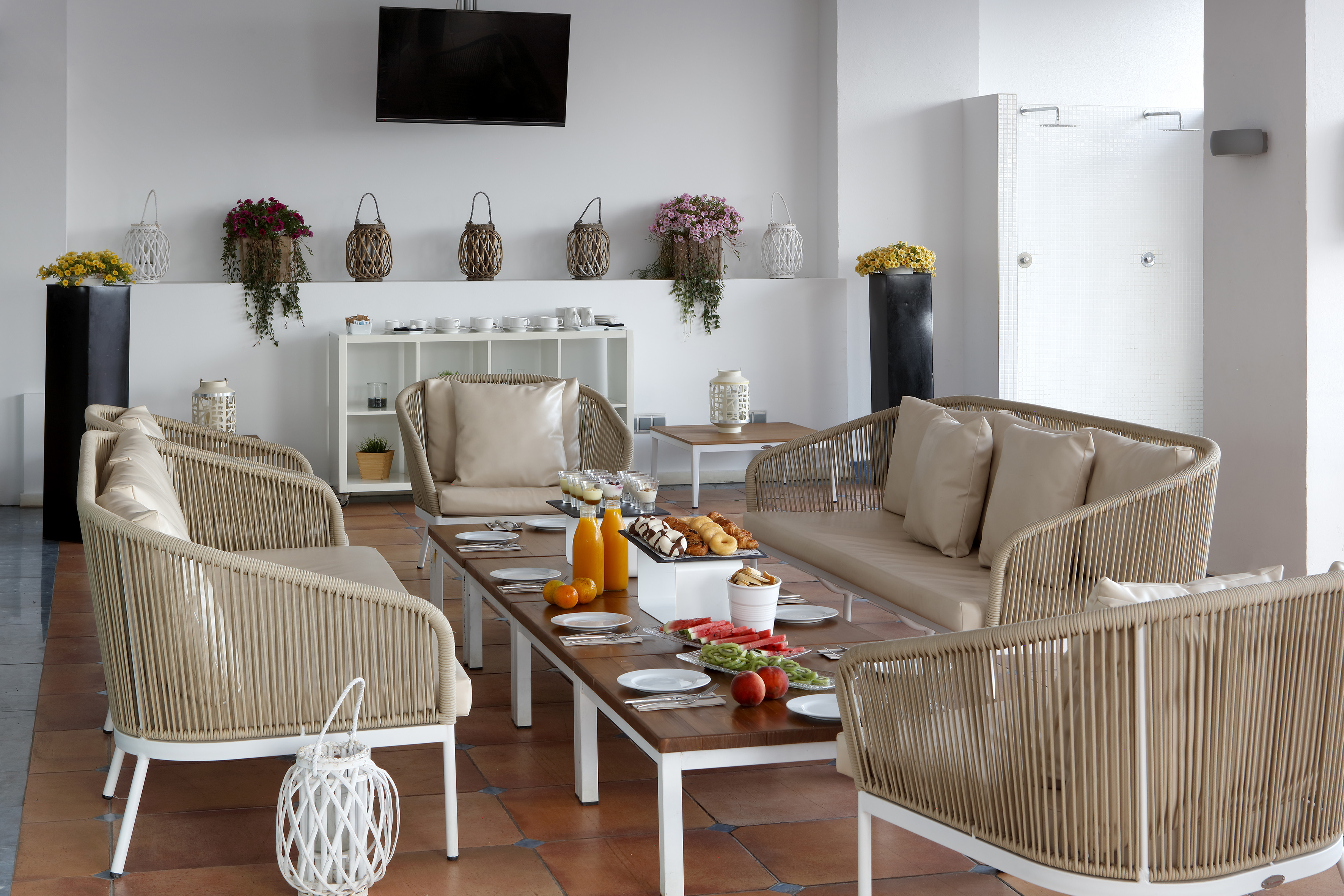 Resort patio breakfast with woven lounge furniture, fruit, pastries, and juice.