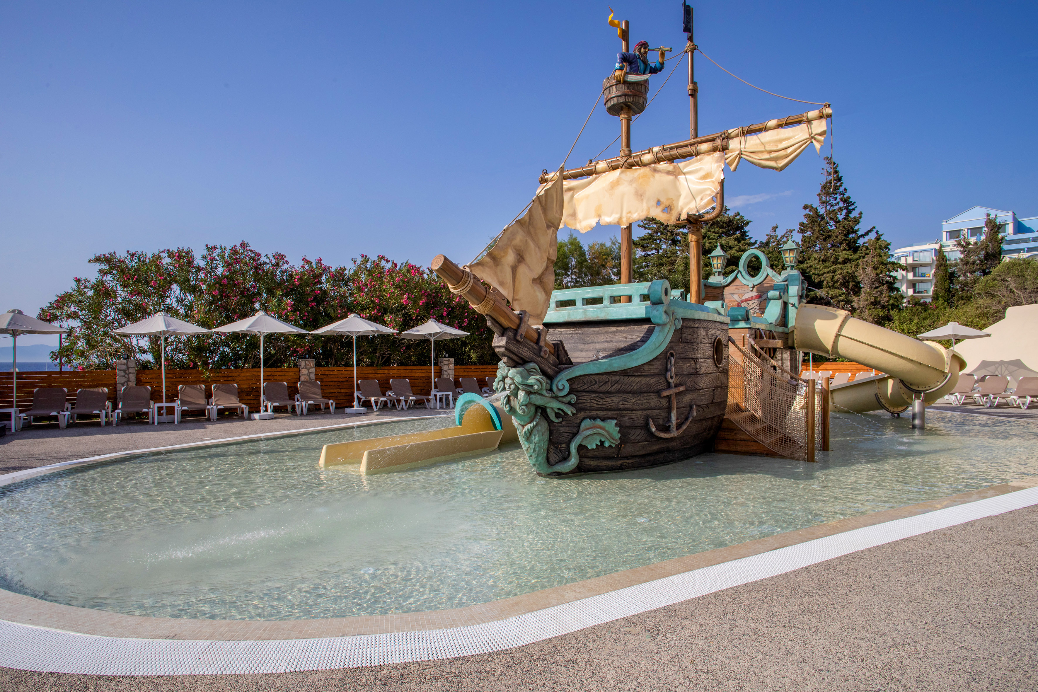 Pirate ship water play area with slides in a children's pool at a resort.