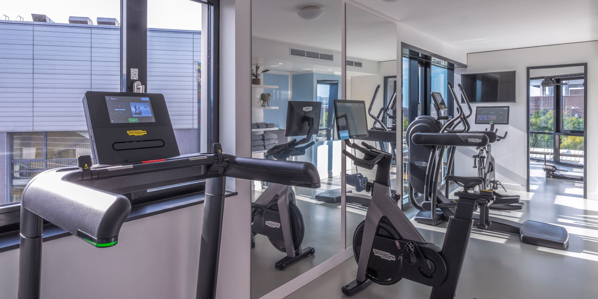 Modern gym with Technogym treadmill, stationary bike, and elliptical. - Khu vực tập thể dục - INNSiDE Wolfsburg, Wolfsburg