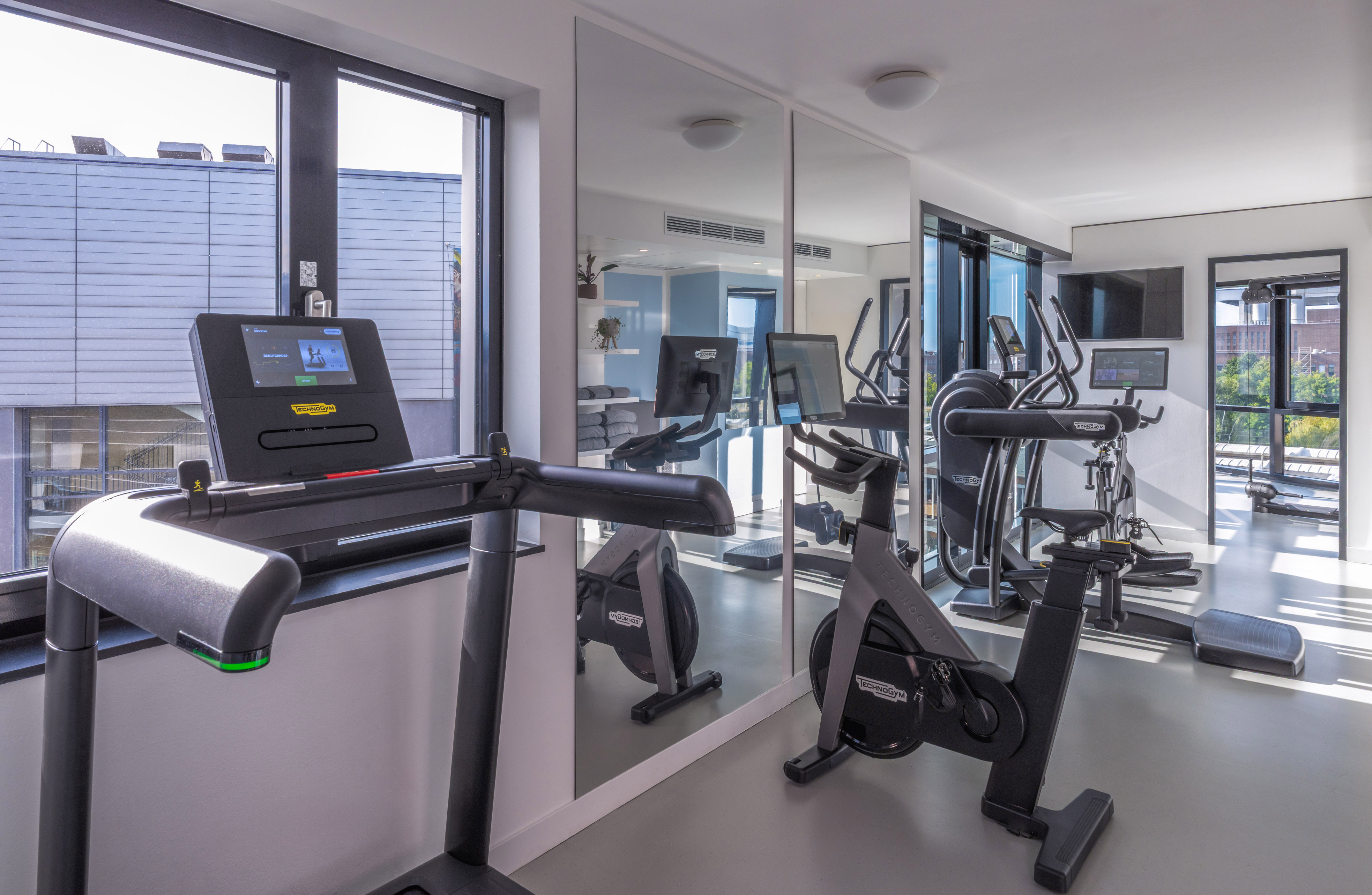 Modern gym with Technogym treadmill, stationary bike, and elliptical. - Khu vực tập thể dục - INNSiDE Wolfsburg, Wolfsburg
