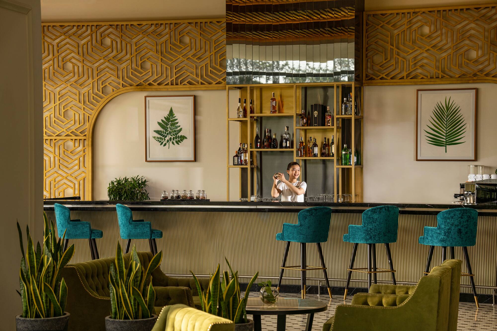 Bartender at modern hotel bar with teal stools and green lounge.