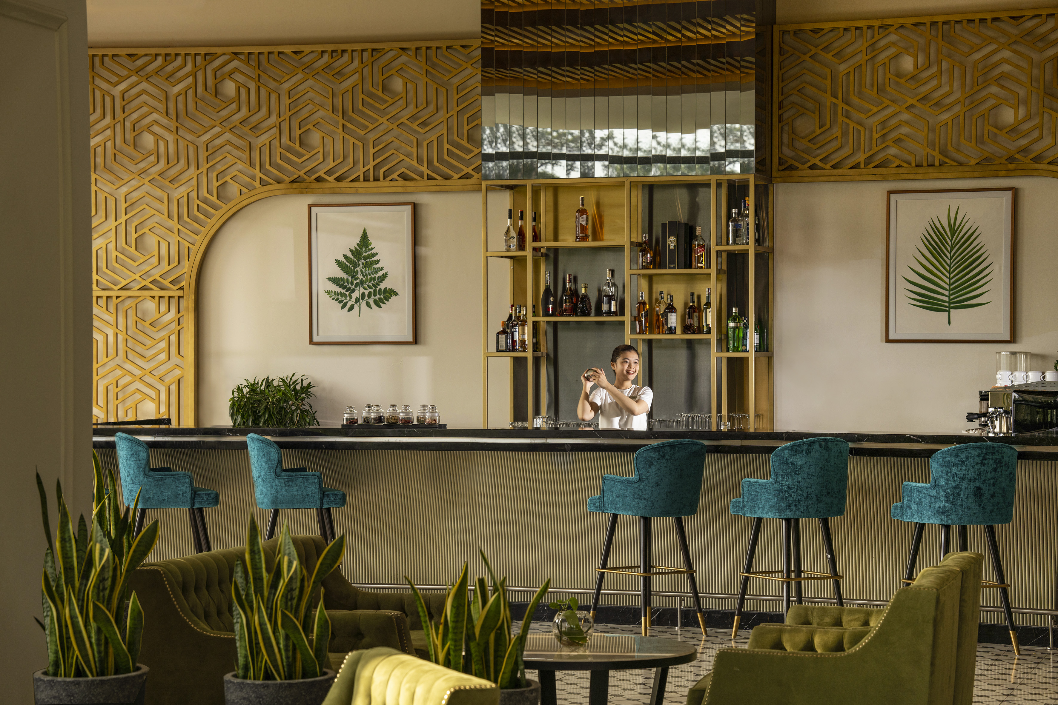 Bartender at modern hotel bar with teal stools and green lounge.