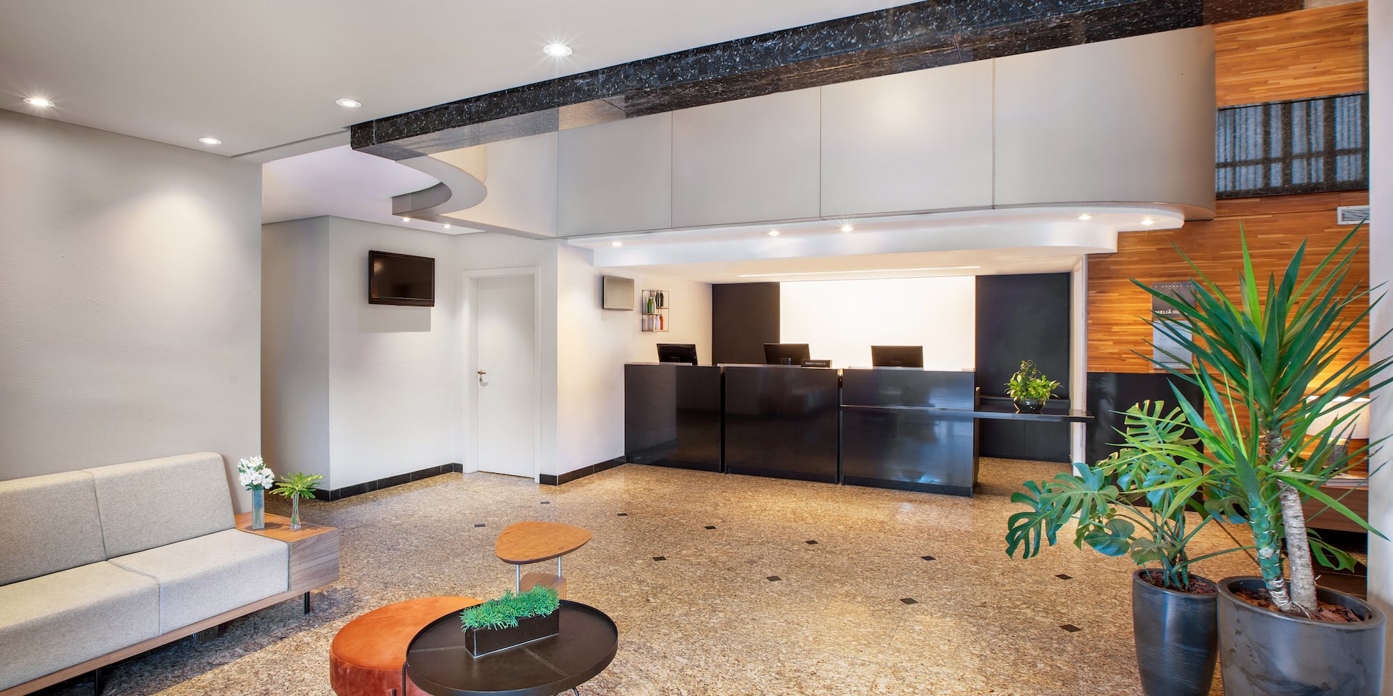 a lobby with a black counter and plants