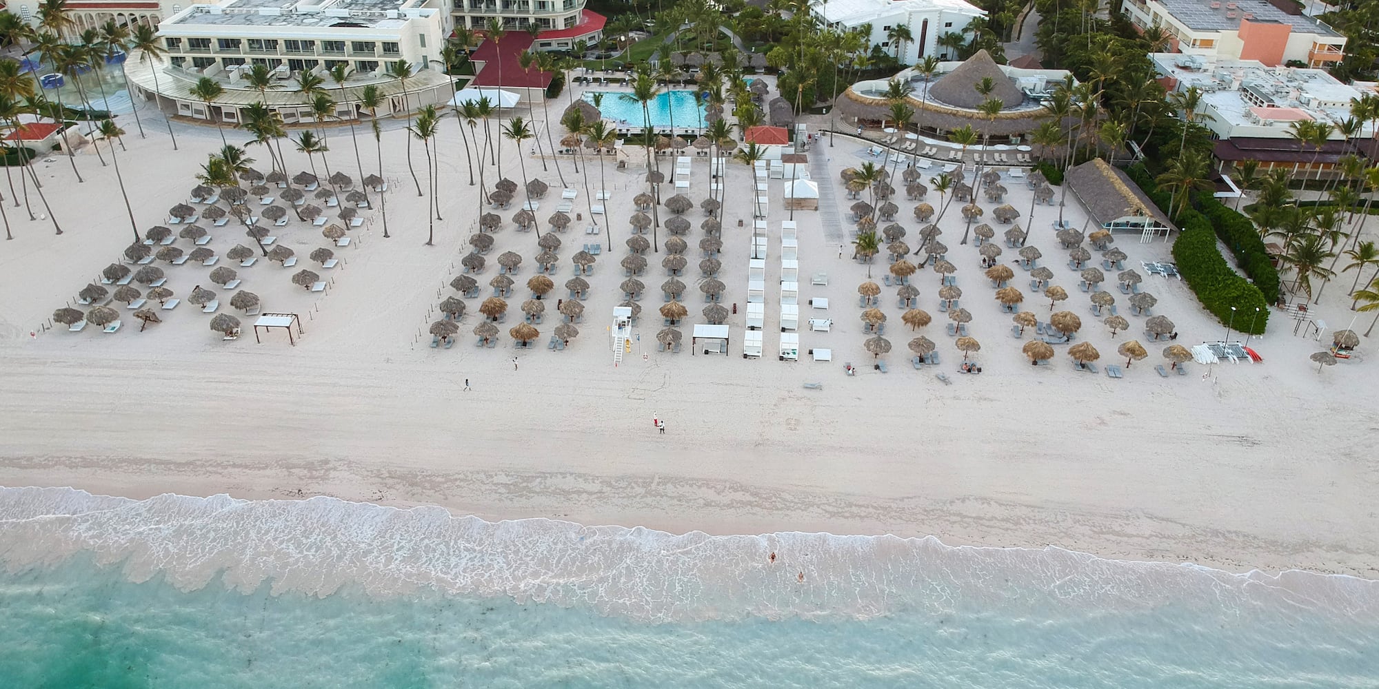 an aerial view of a beach with umbrellas and chairs