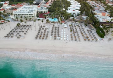 an aerial view of a beach with umbrellas and chairs