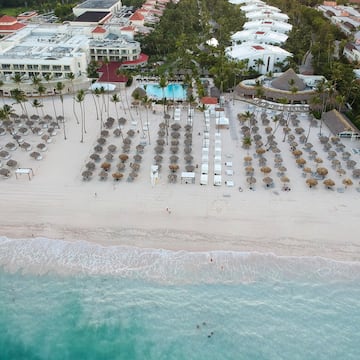 an aerial view of a beach with umbrellas and chairs