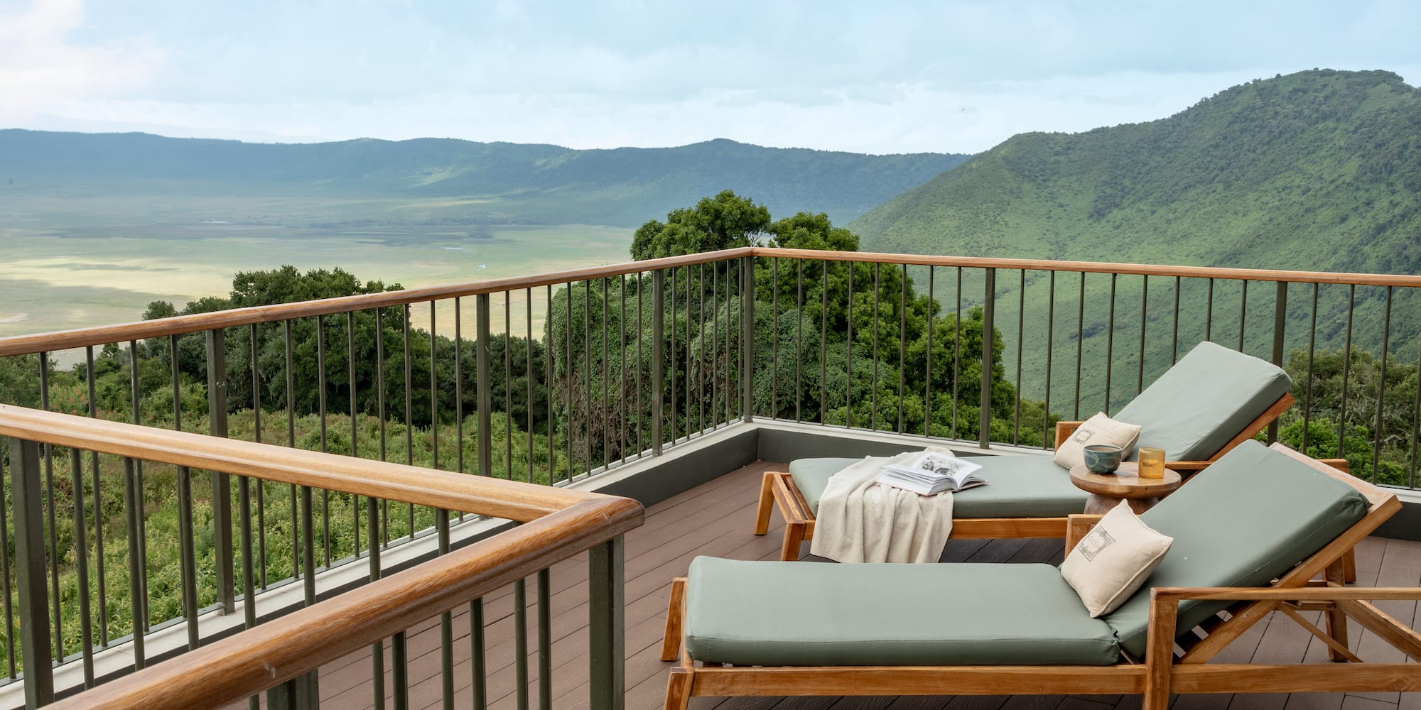 a deck with chairs and a railing overlooking a valley