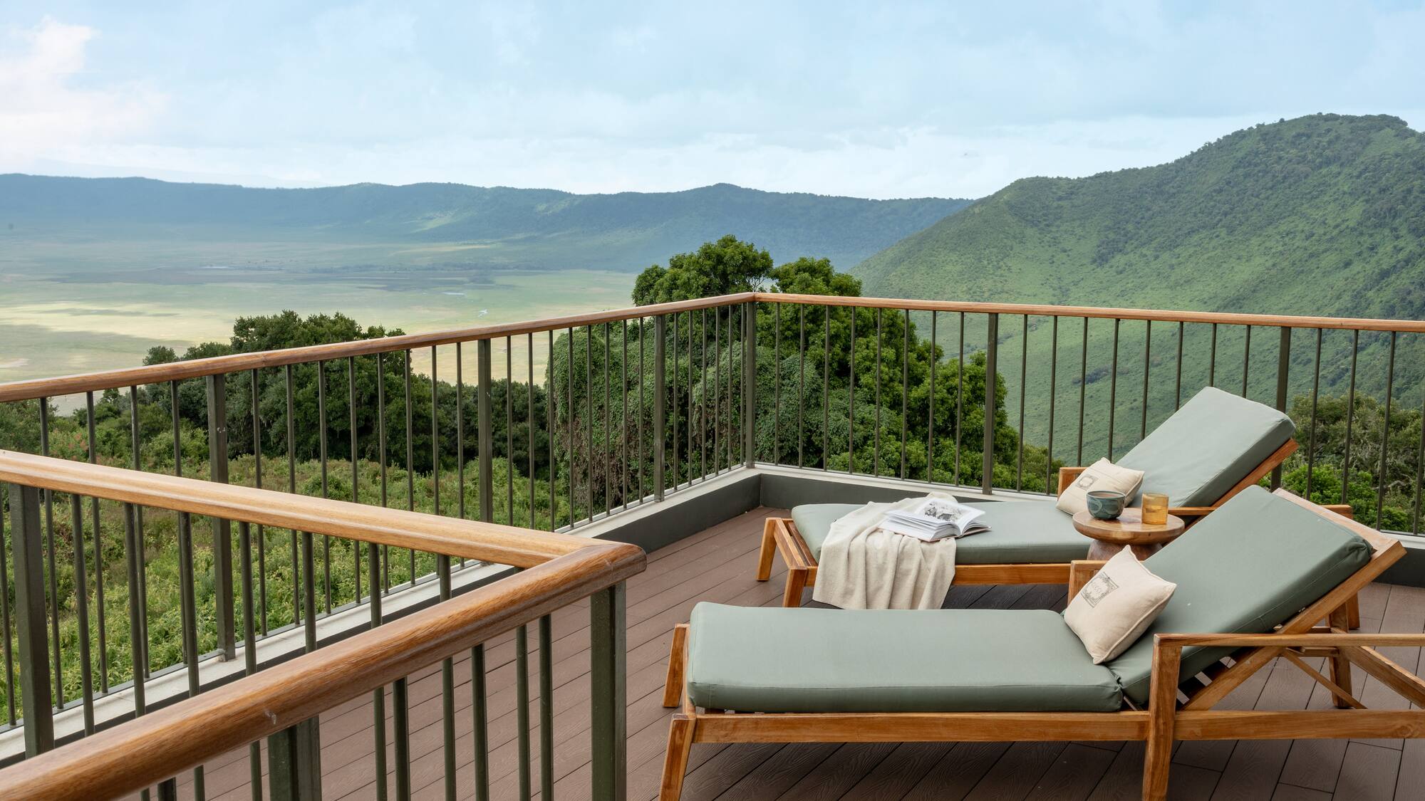 a deck with chairs and a railing overlooking a valley
