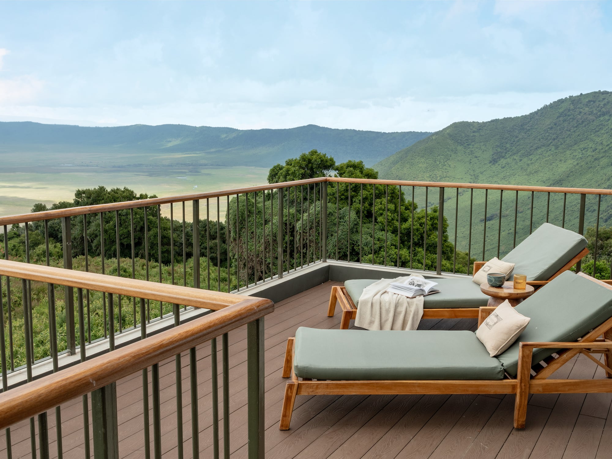 a deck with chairs and a railing overlooking a valley