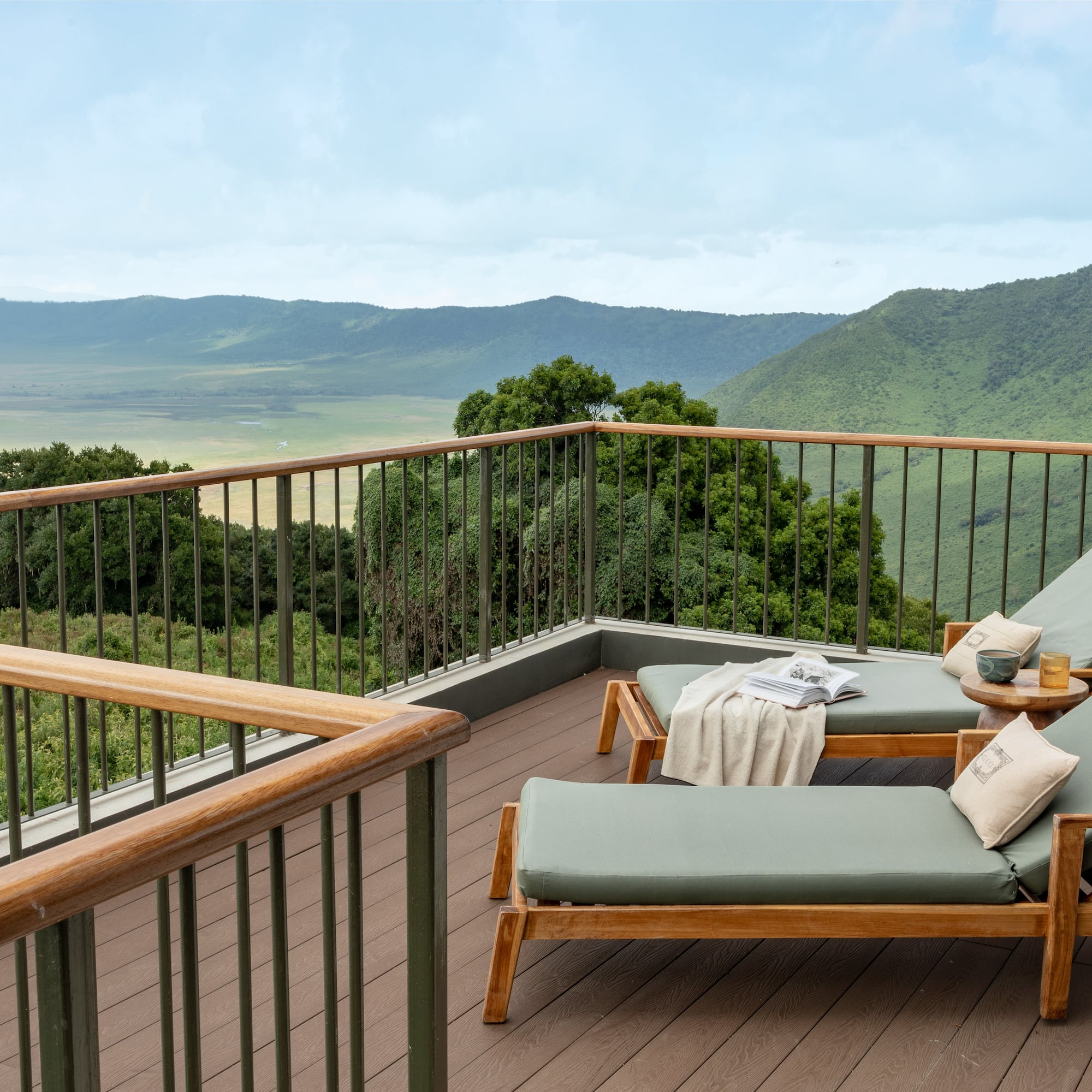 a deck with chairs and a railing overlooking a valley