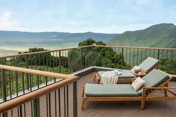 a deck with chairs and a railing overlooking a valley