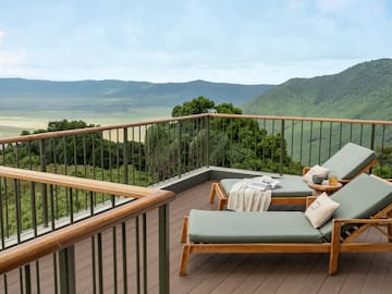 a deck with chairs and a railing overlooking a valley
