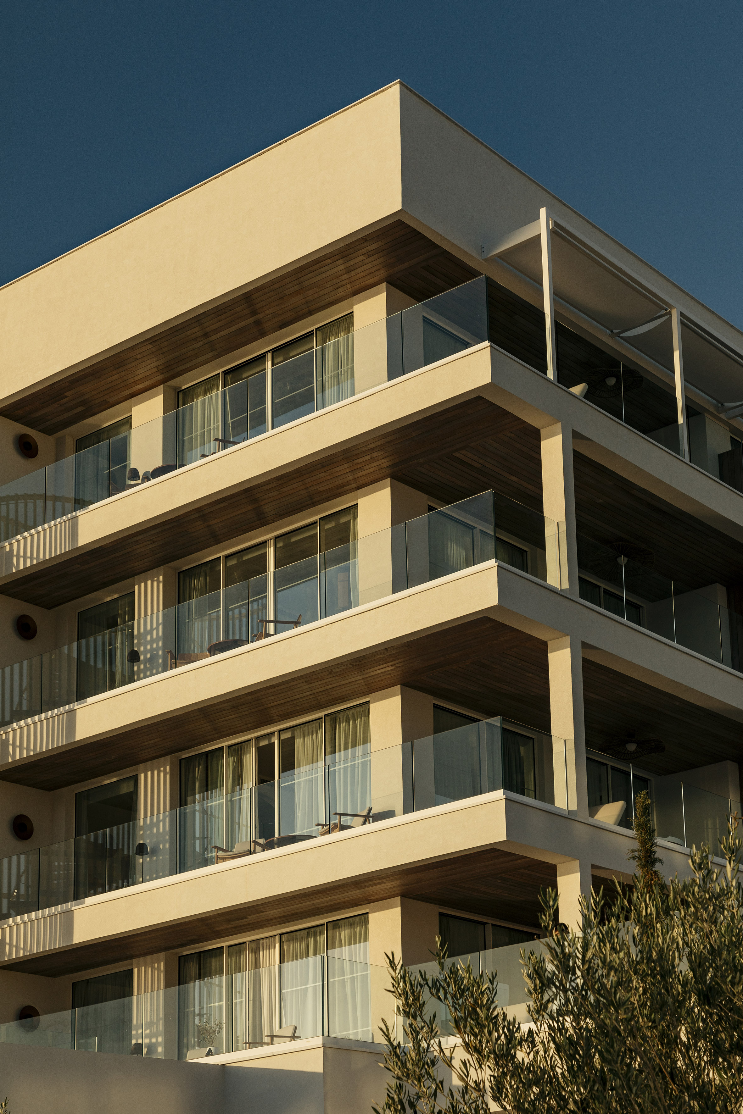Modern resort building with tiered glass balconies and warm evening light.