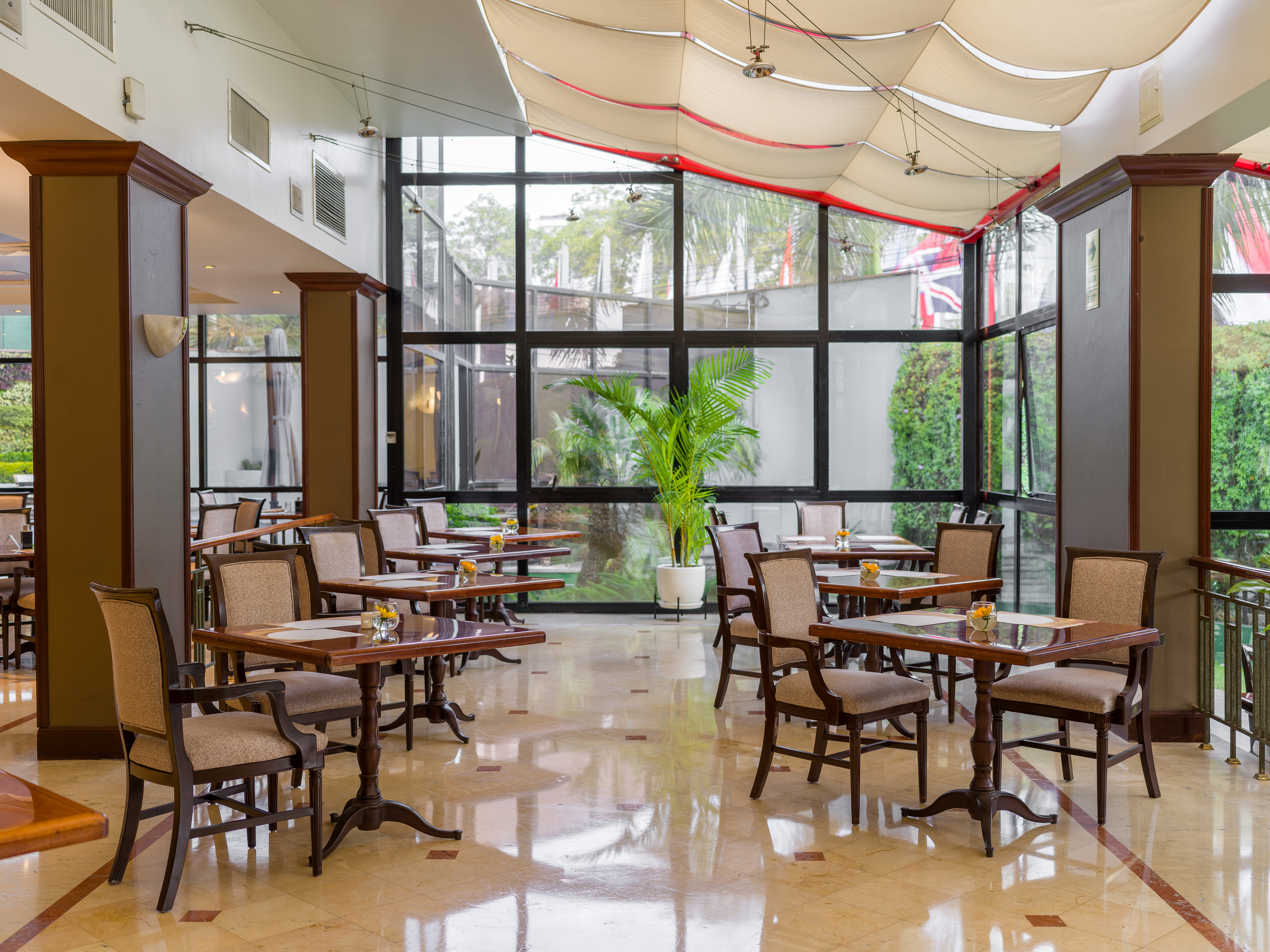 Spacious hotel restaurant with elegant tables, chairs, and large windows.