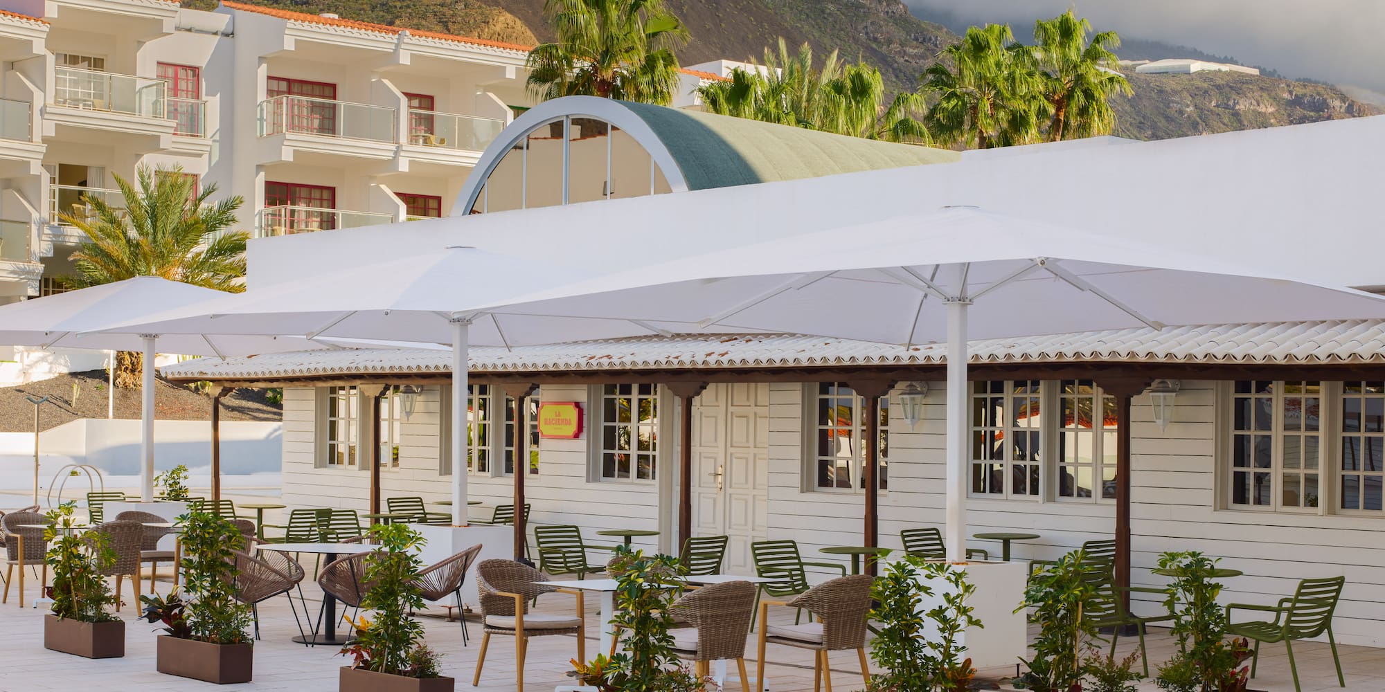a white building with tables and chairs and umbrellas