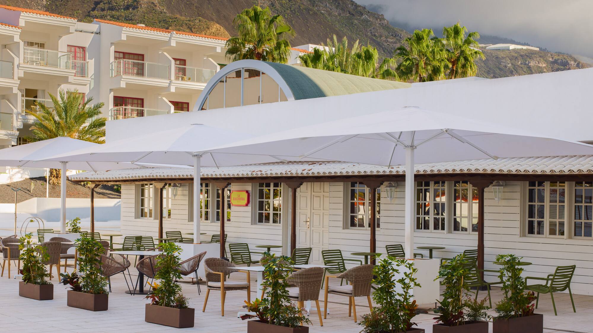 a white building with tables and chairs and umbrellas