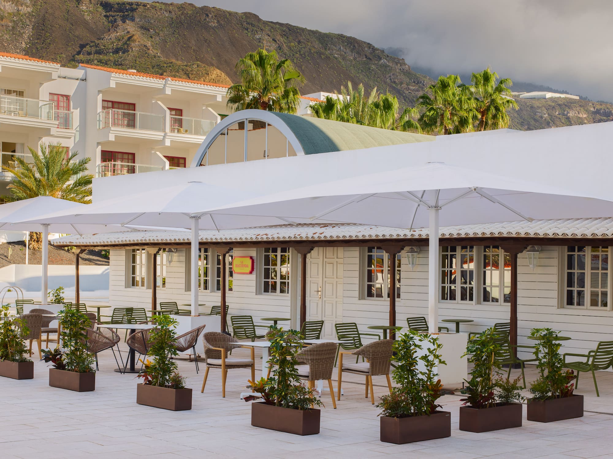 a white building with tables and chairs and umbrellas