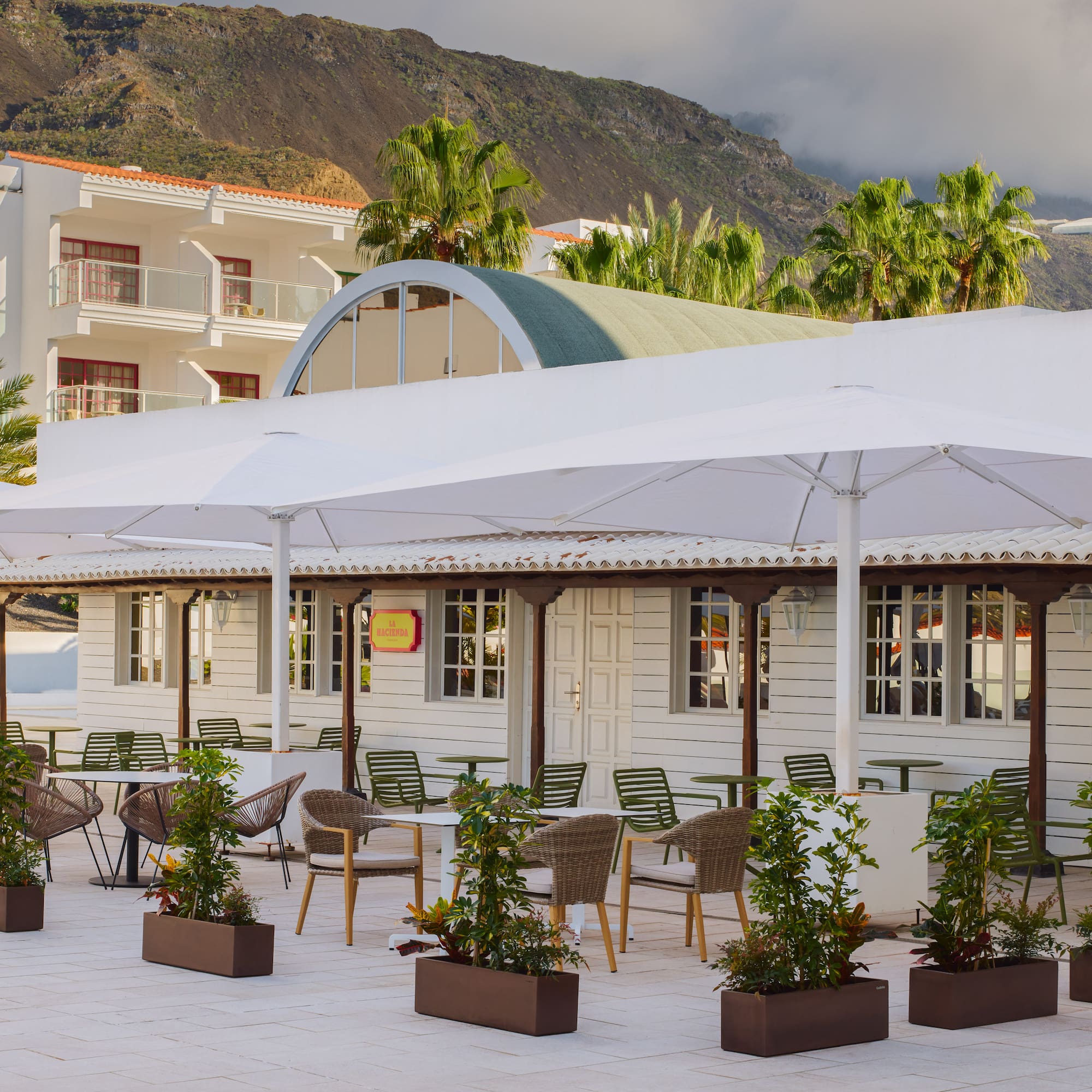 a white building with tables and chairs and umbrellas